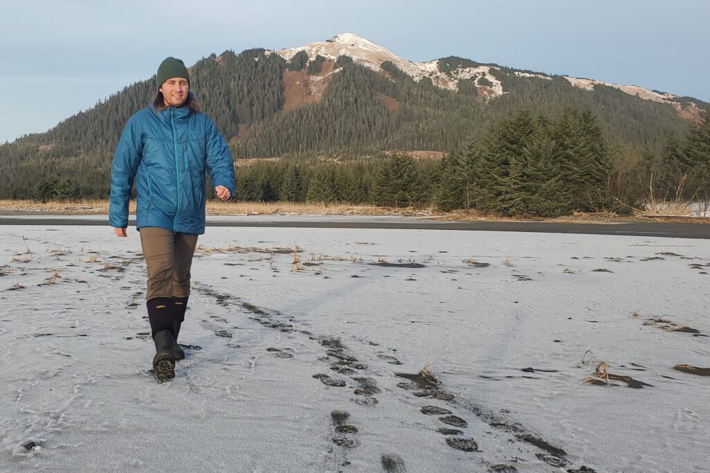 A man walks along a snowy beach