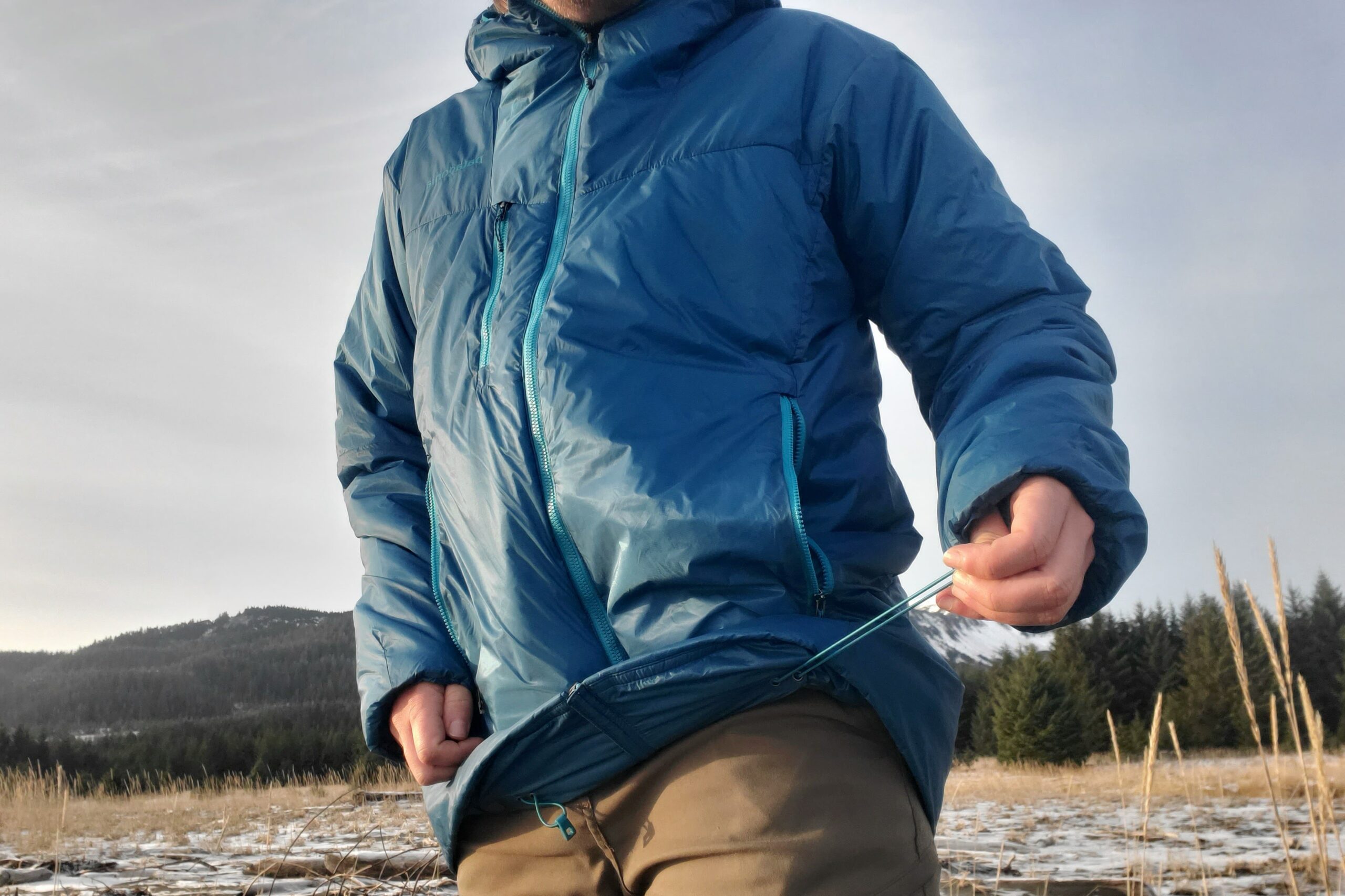 A man tightens the hem of his jacket.