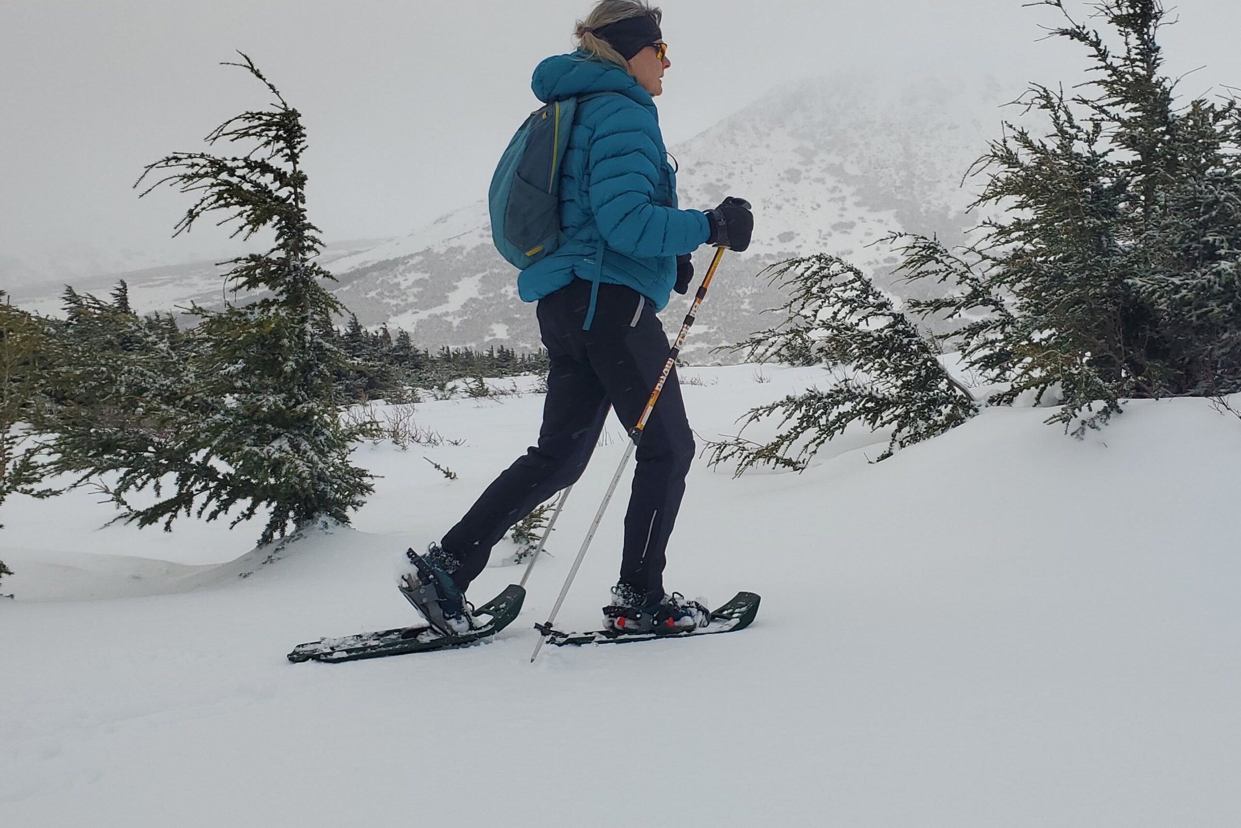 A woman walks through deep snow in snowshoes.