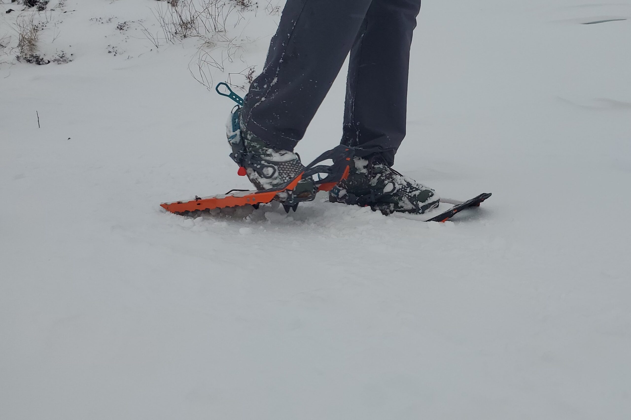 A man walks through snow wearing snowshoes