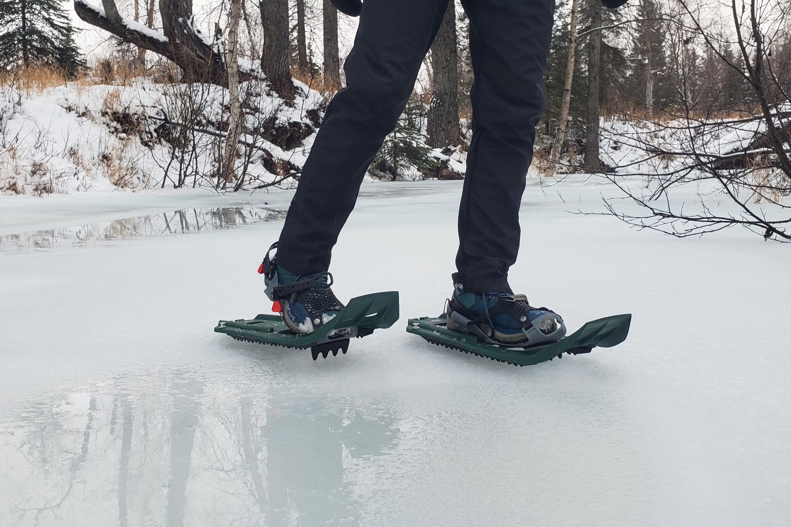 Snowshoes walking along an icy river.