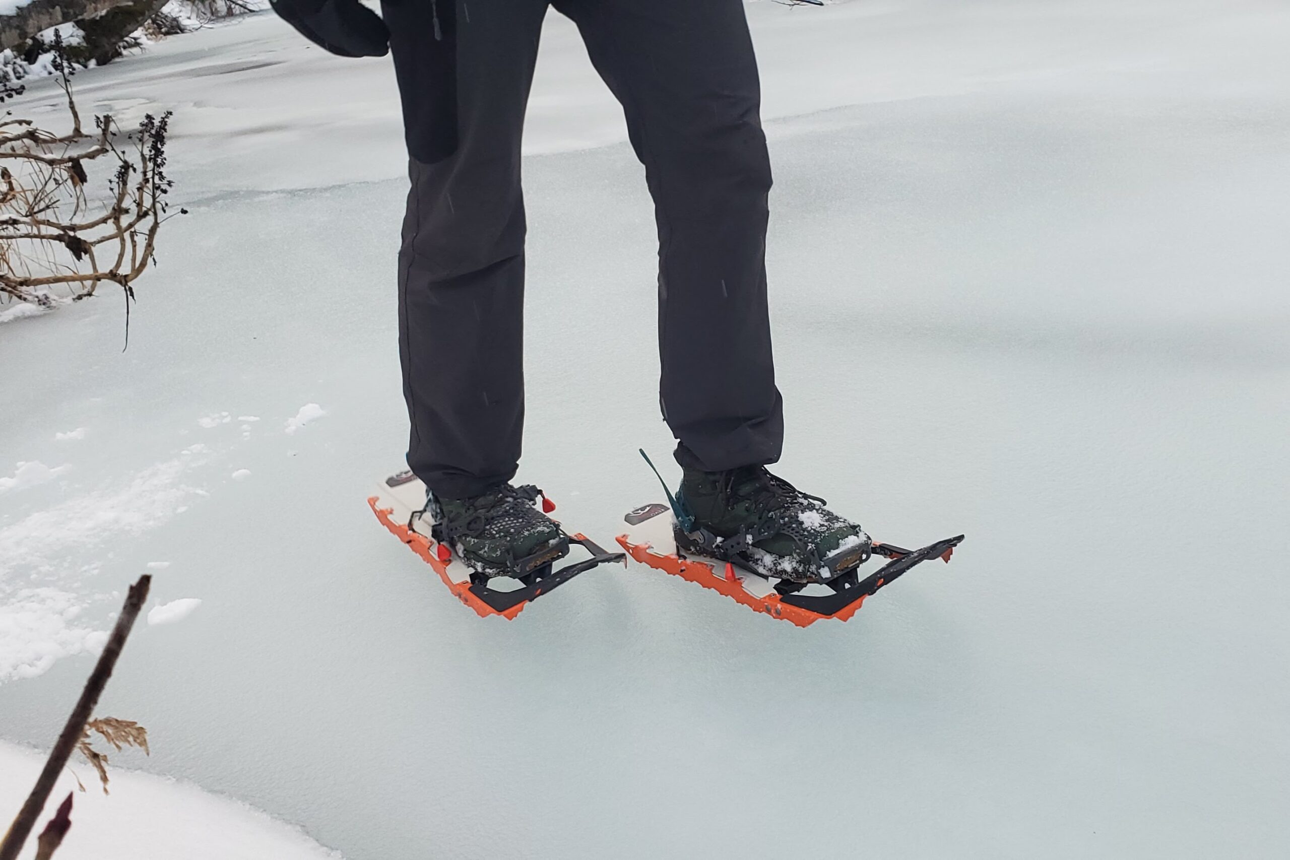 A man walks along an icey river in snowshoes