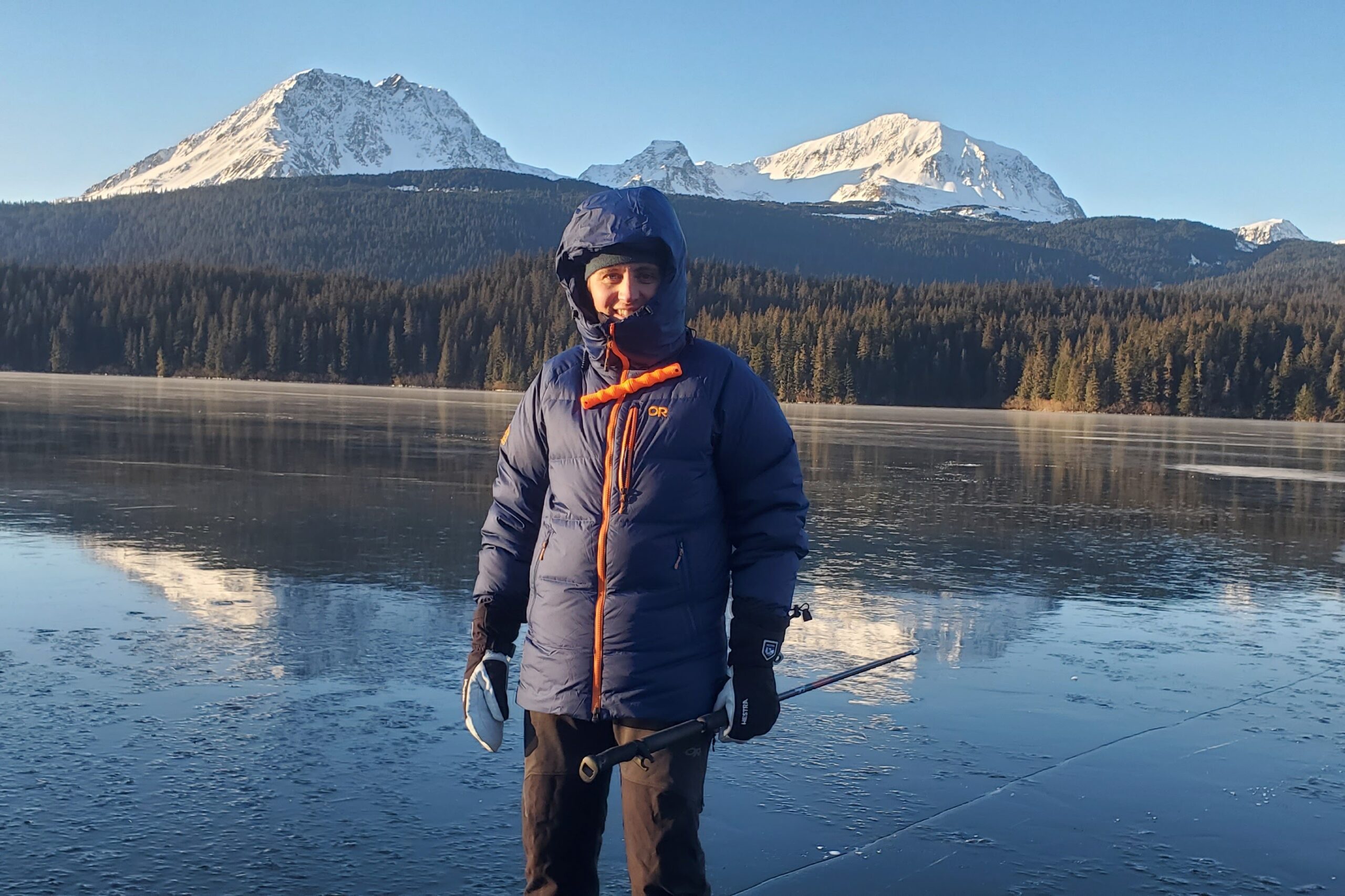 A man ice skates in front of a mountain view