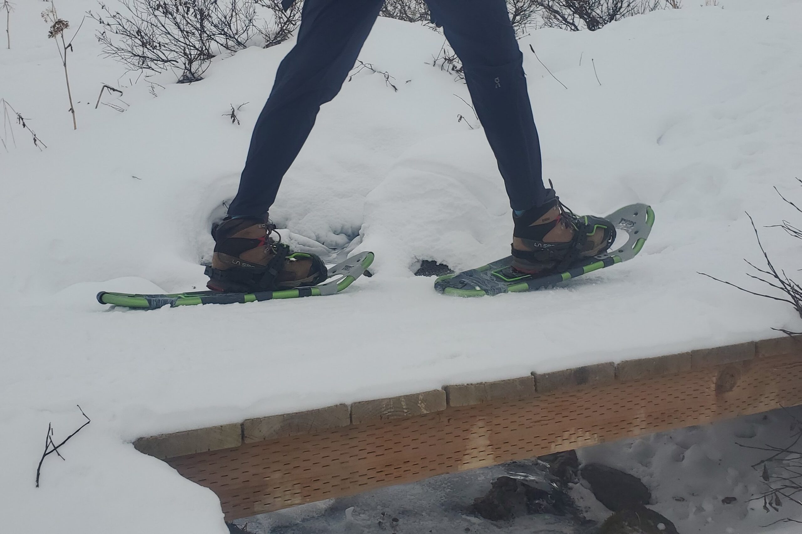 A person walks across a bridge wearing snowshoes