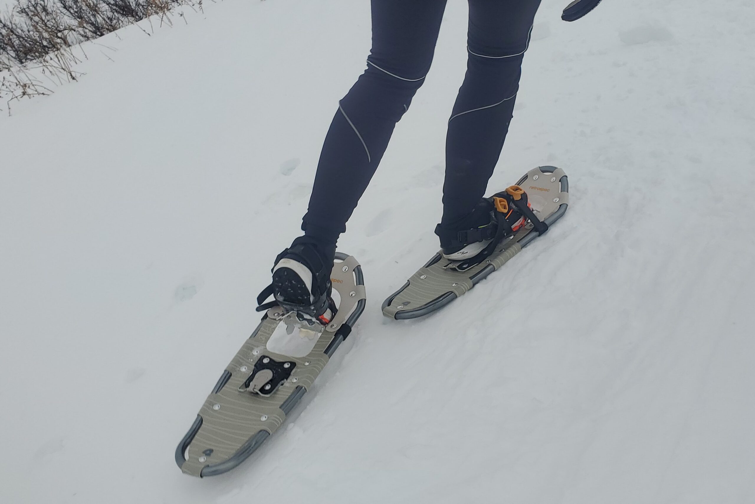 A person wearing snowshoes walks uphill