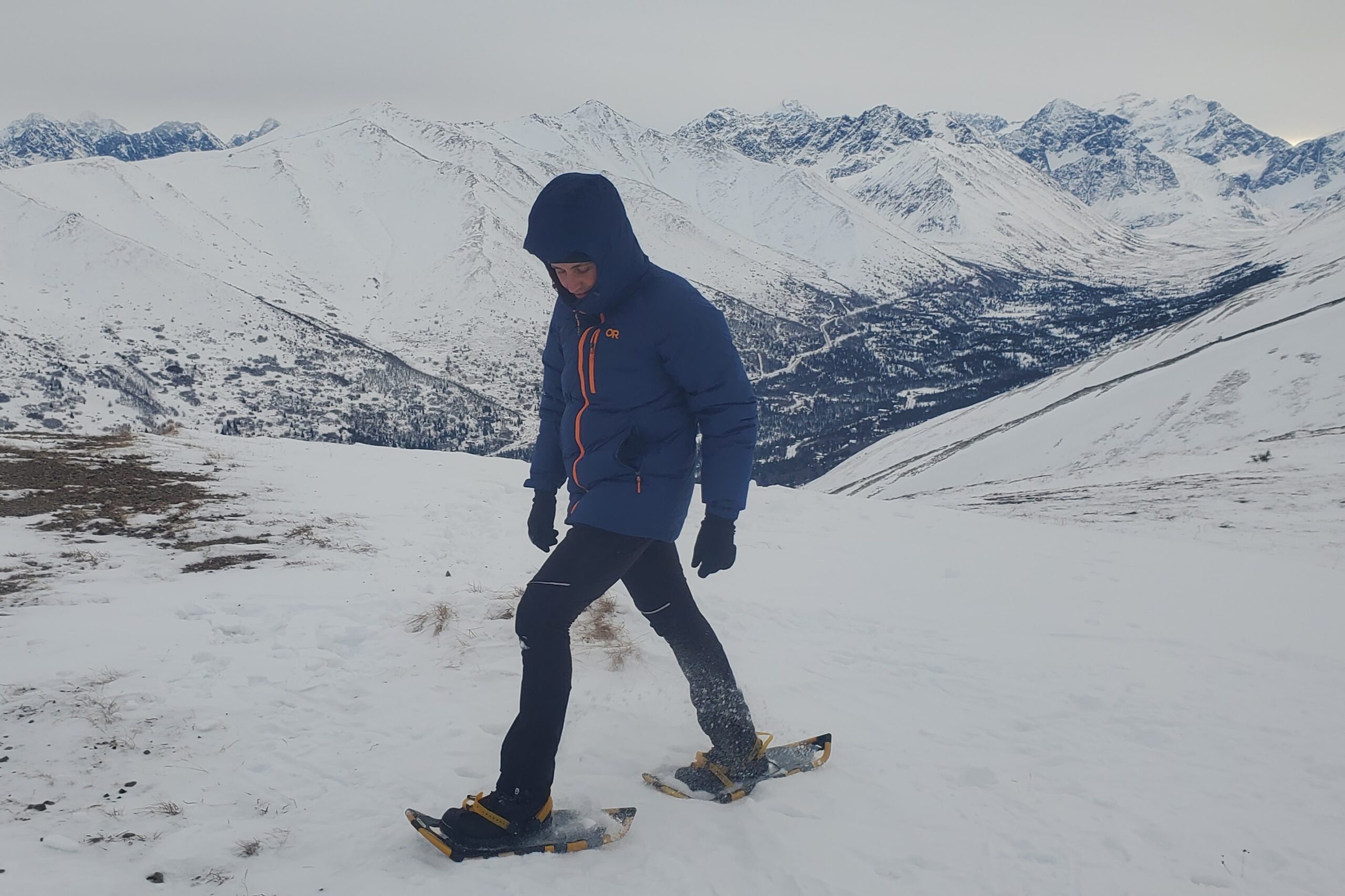 A man snowshoes on a mountain ridgeline.