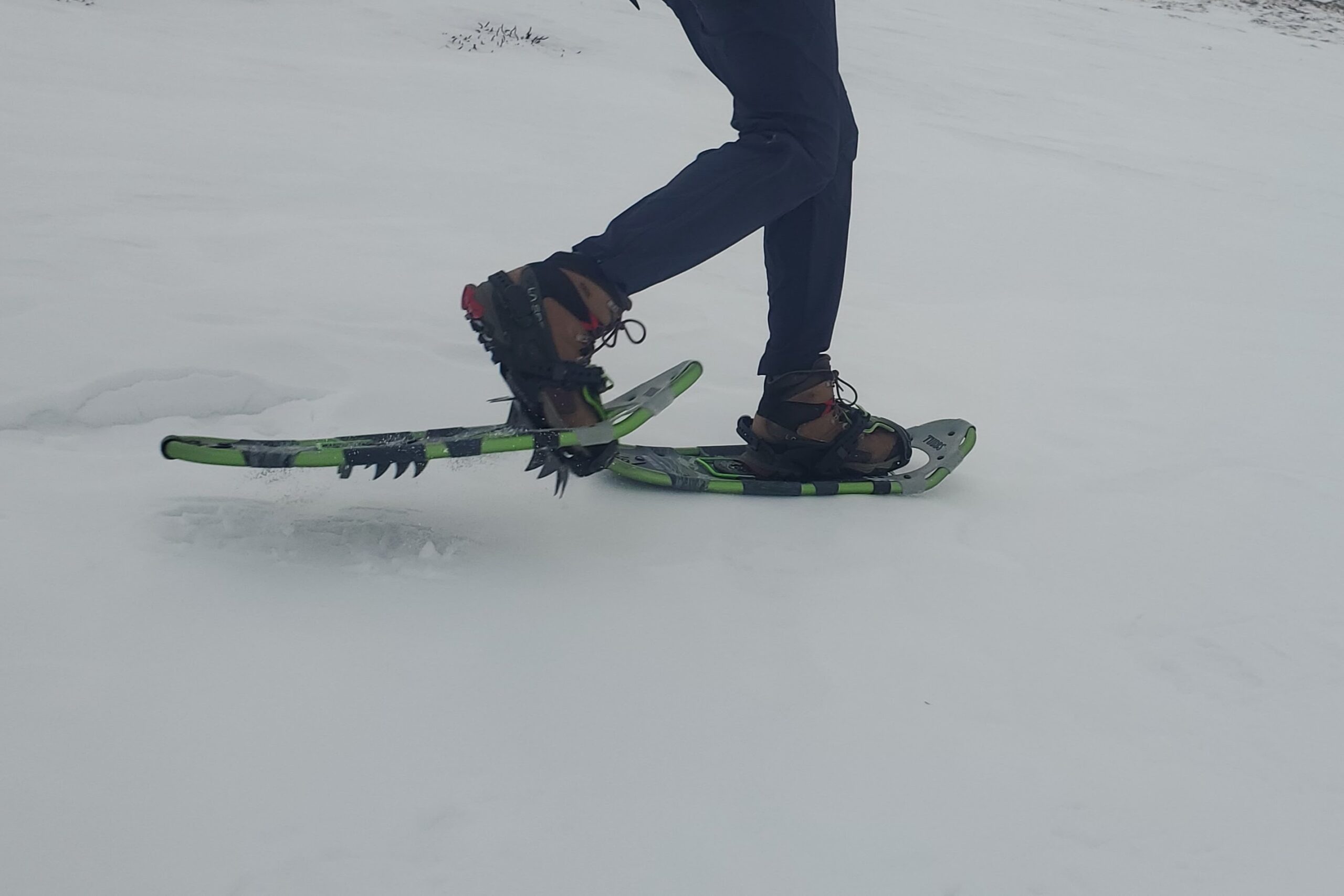 A person walks wearing snowshoes mid stride