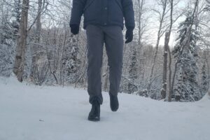 A man walks toward the camera on a snowy trail.