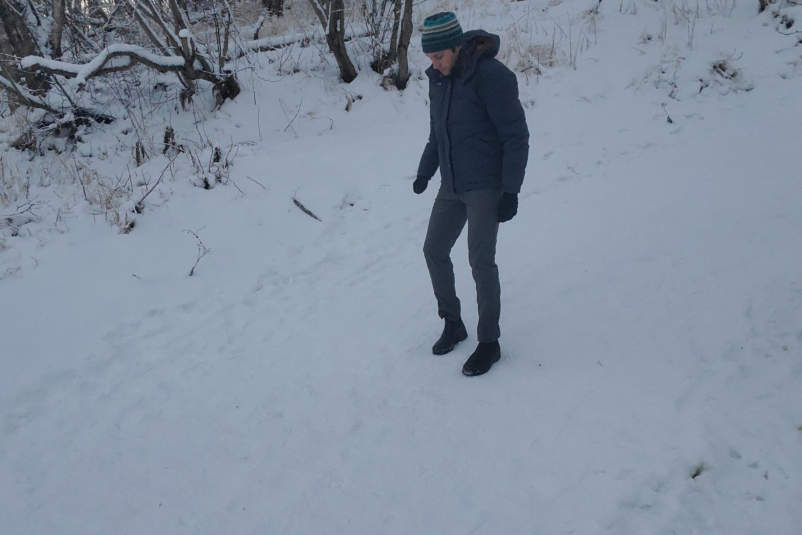 A man walks down a snowy trail.