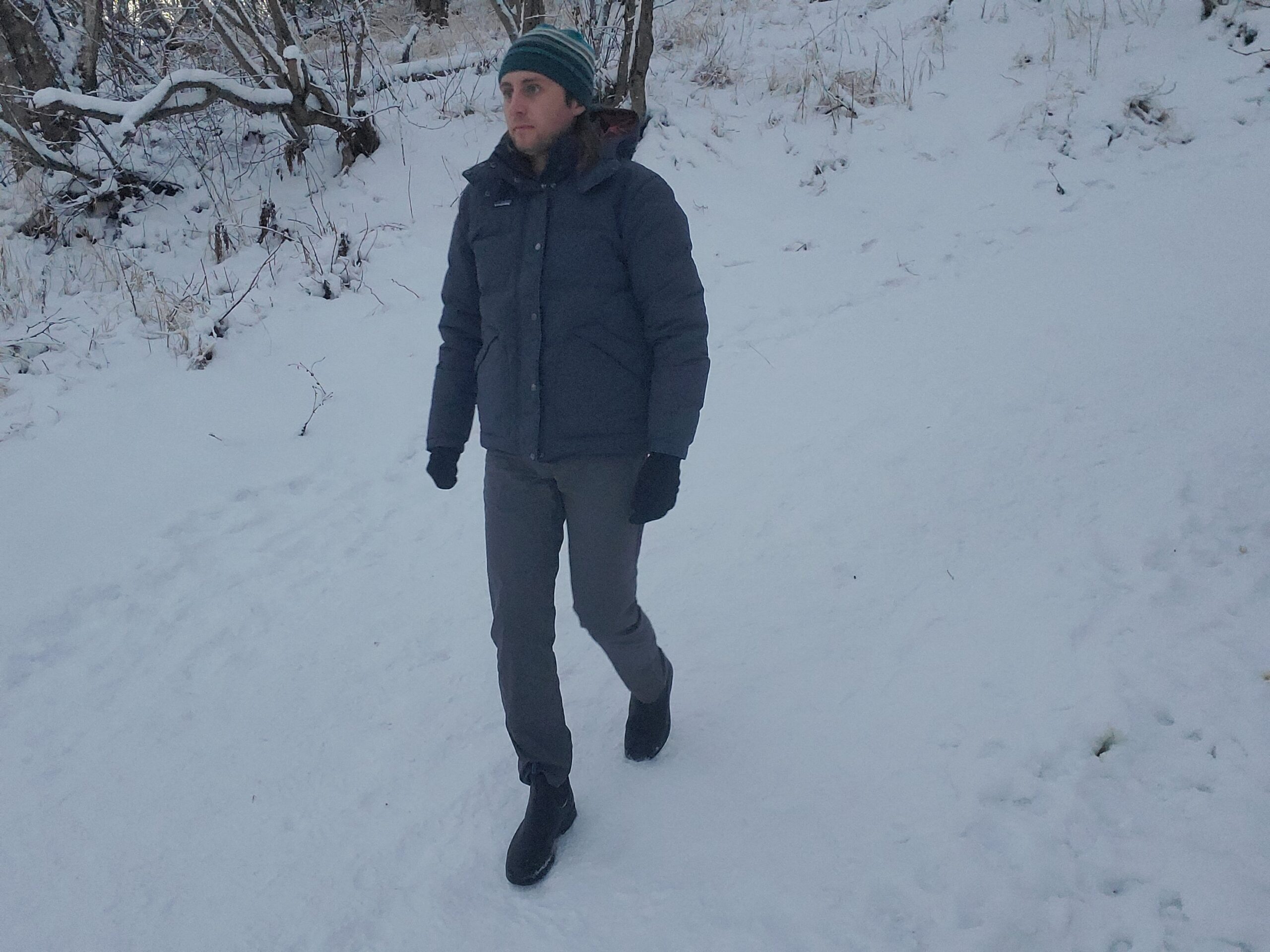 A man walks down a snowy trail.