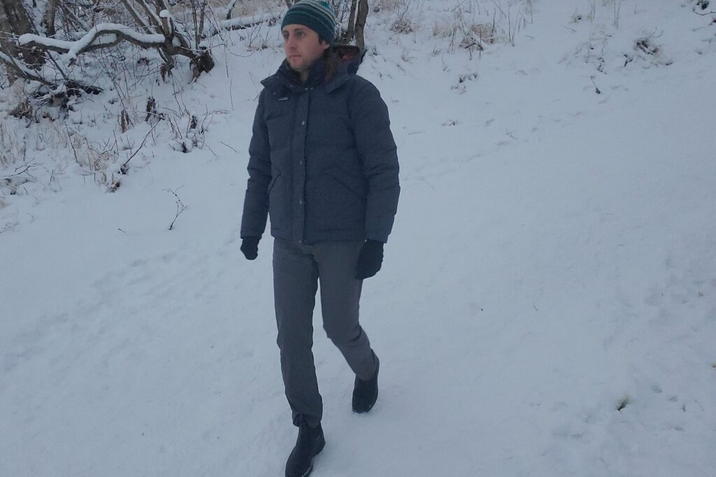 A man walks down a snowy trail.