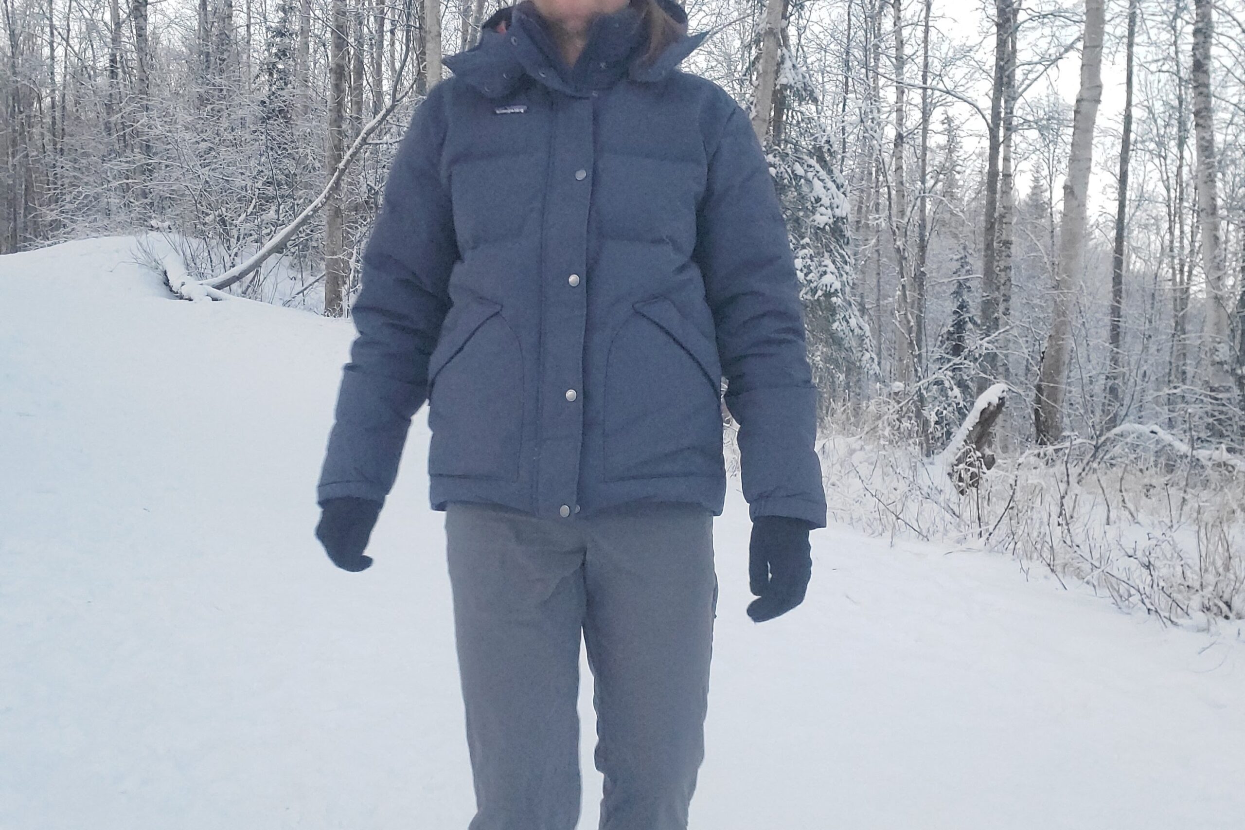 A closeup of a man walking toward the camera on a snowy trail.