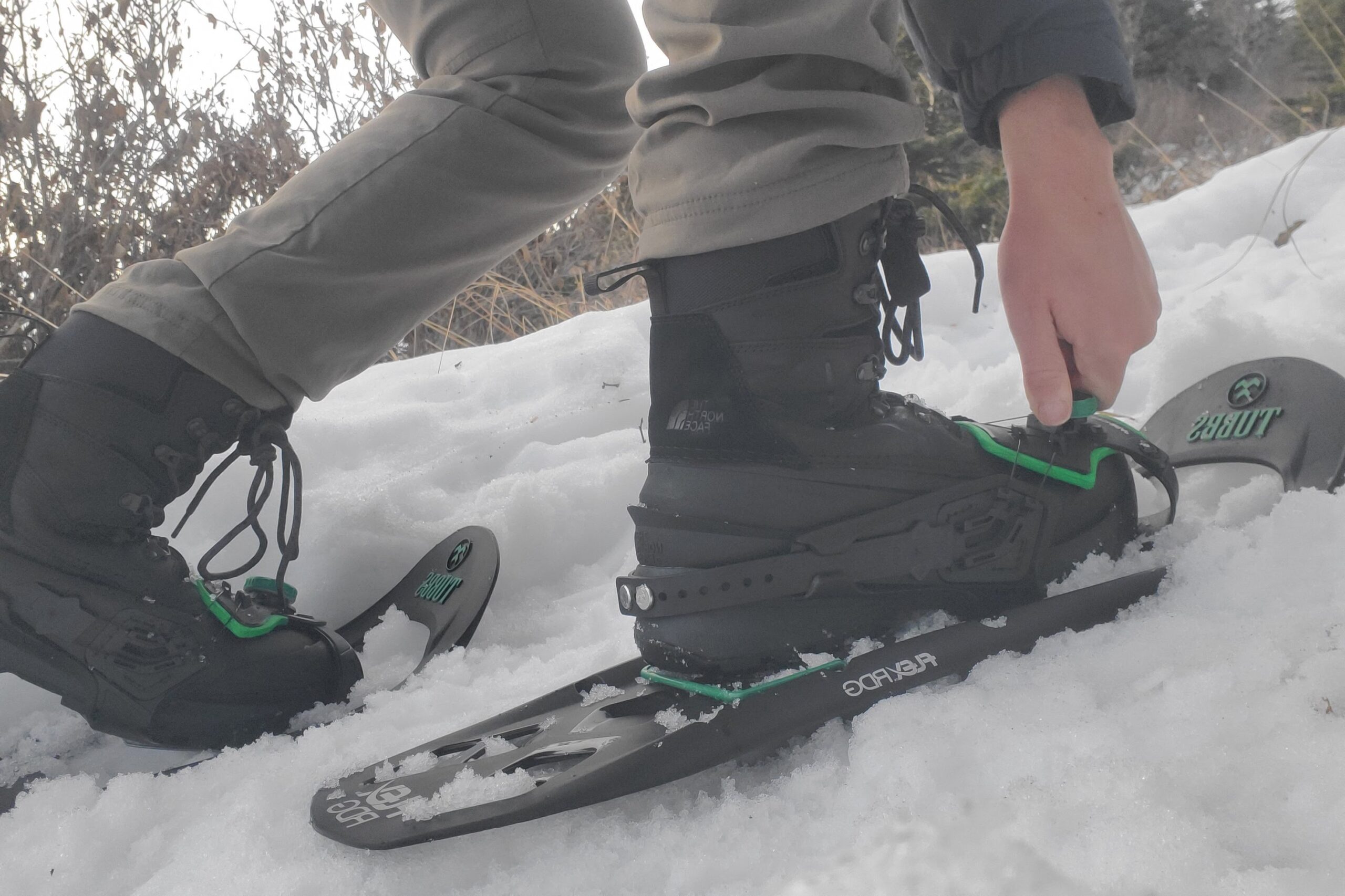 A man puts on a pair of black snowshoes