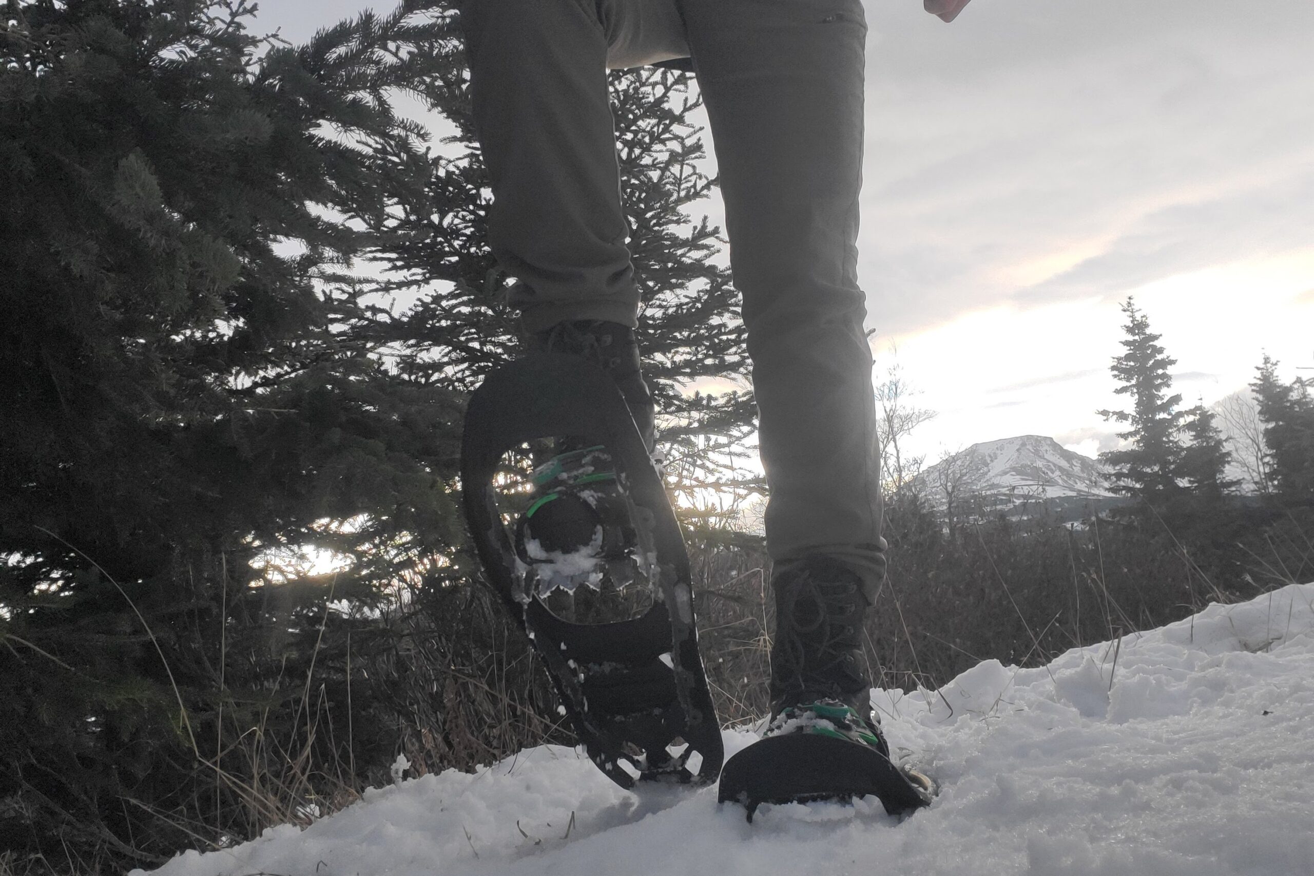 A man walks towards the camera on a snowy trail