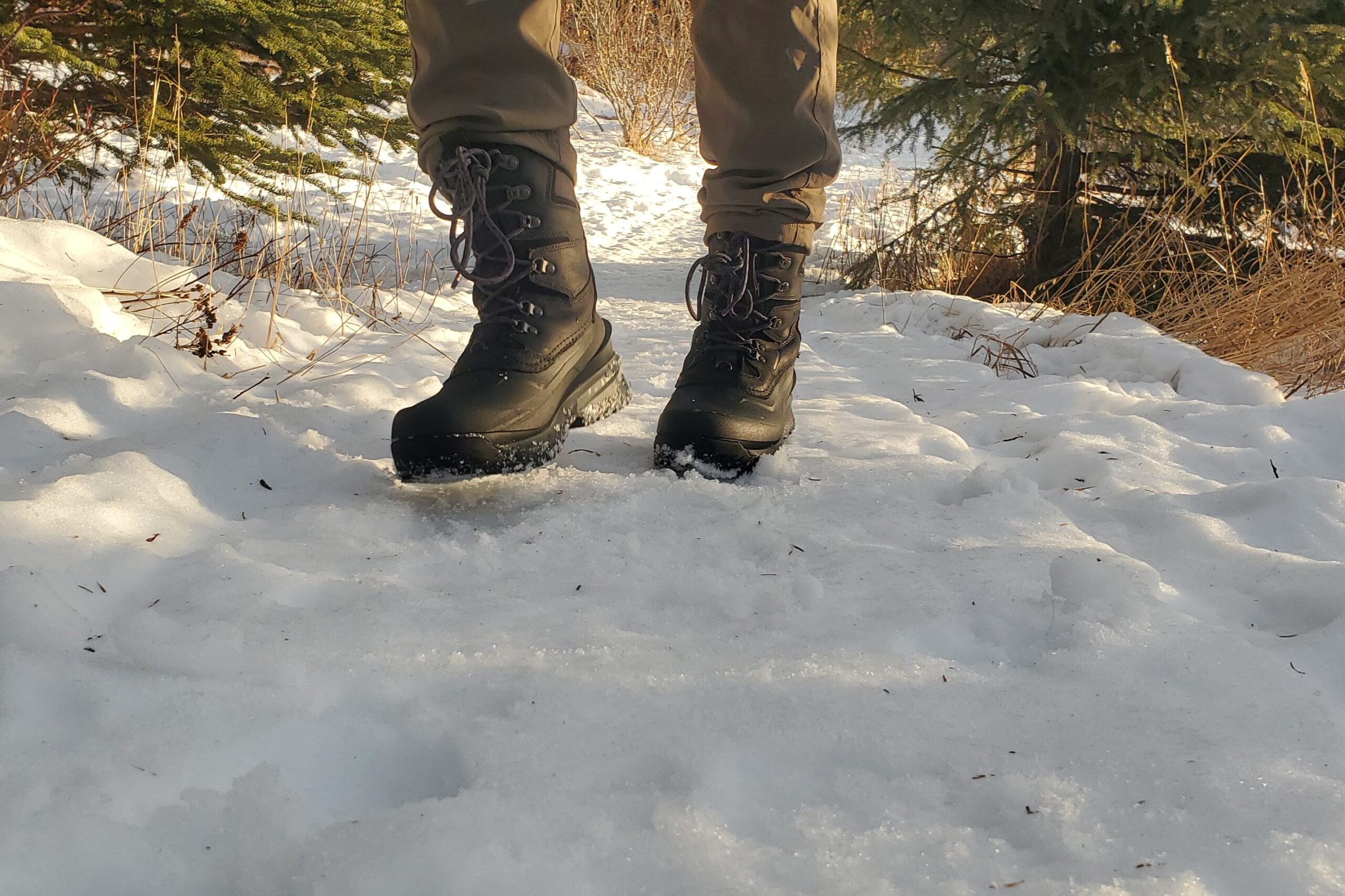 A pair of boots walks toward the camera on a winter trail.