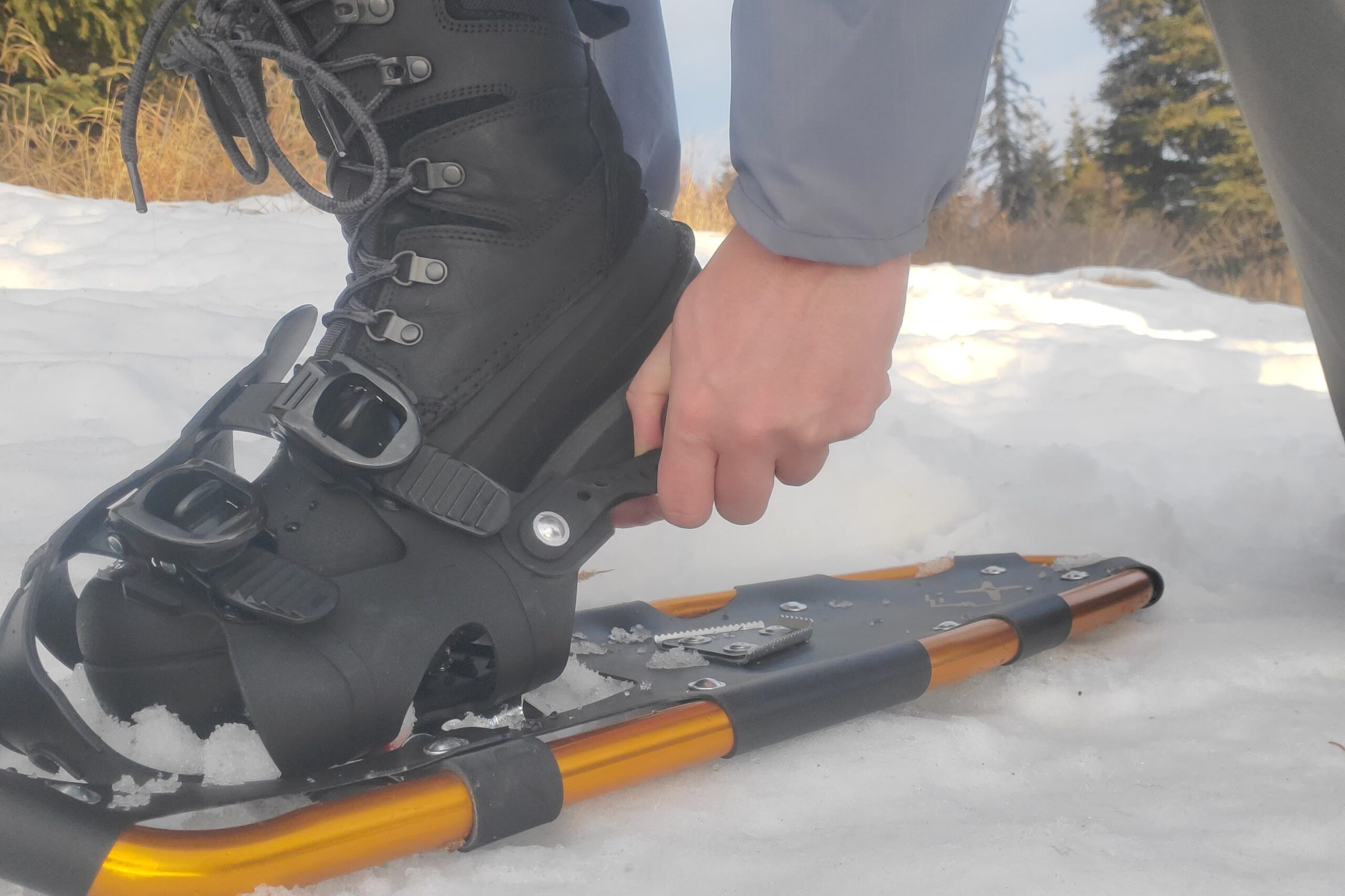 A man secures the heel strap on snowshoes.