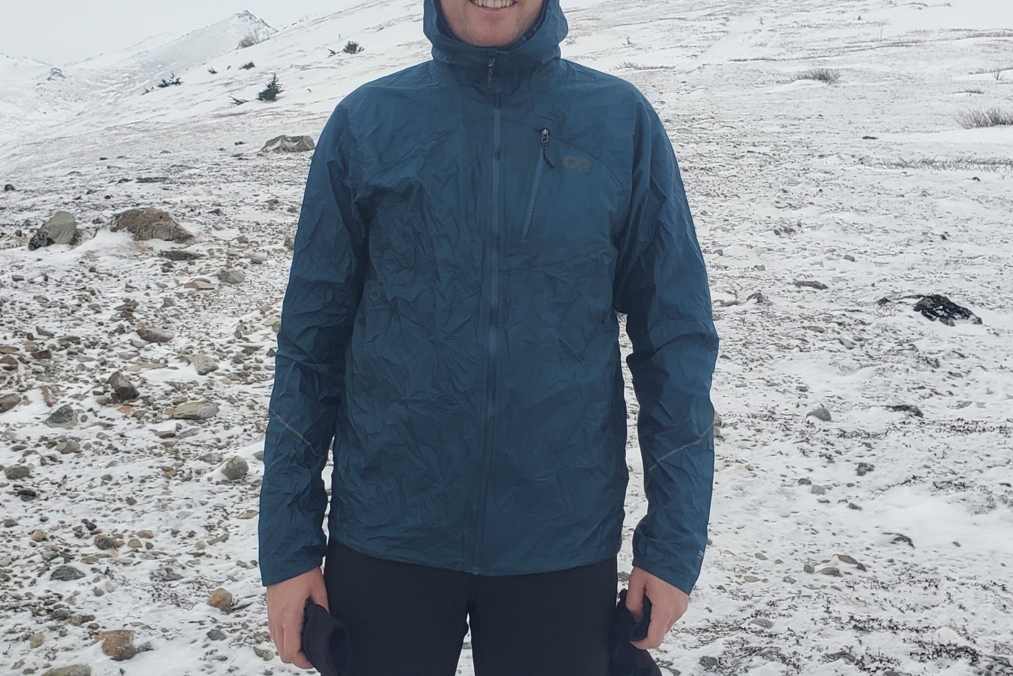 A man stands on a snowy mountainside facing the camera.