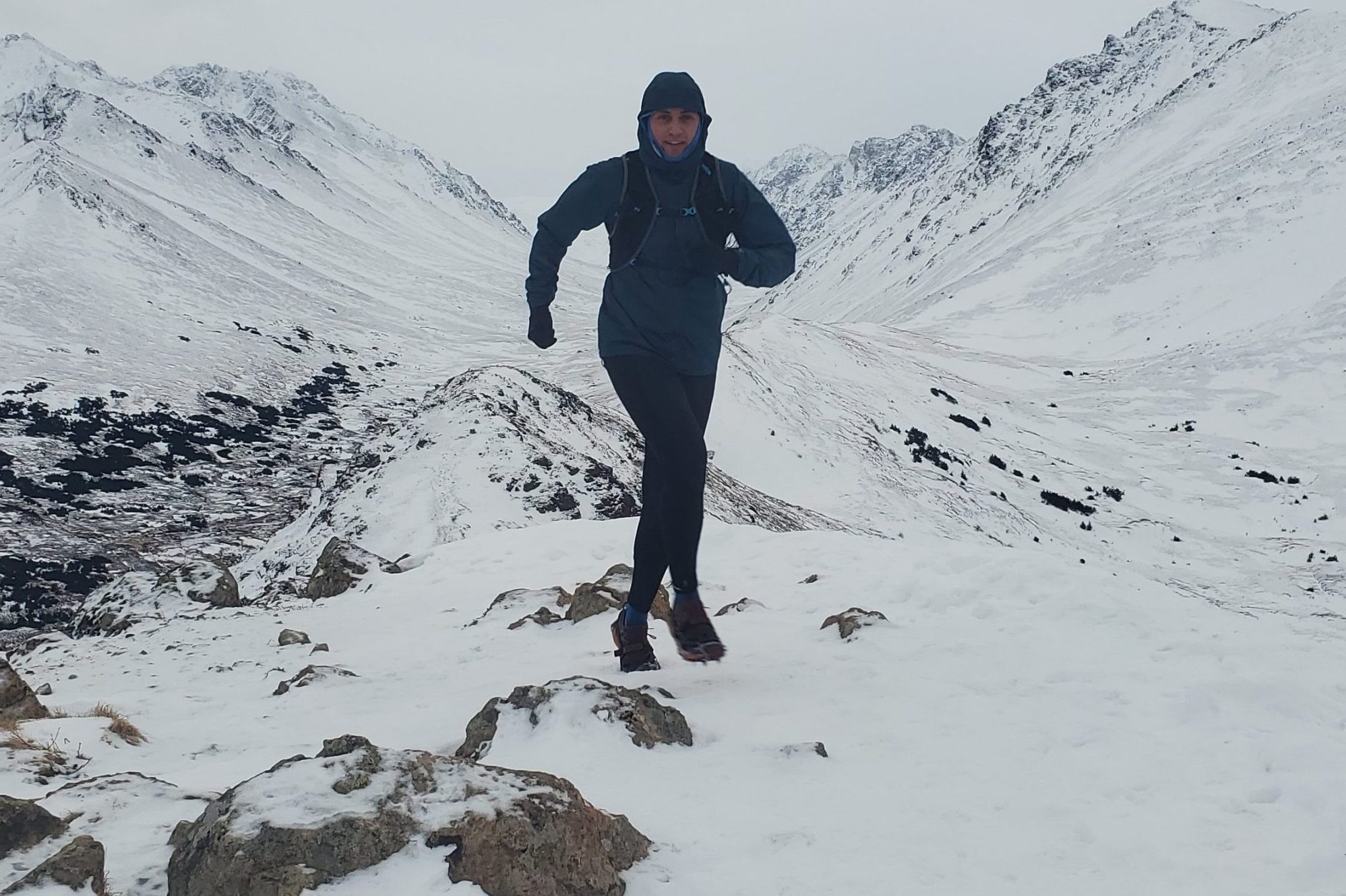 A man runs along a snowy ridgeline.