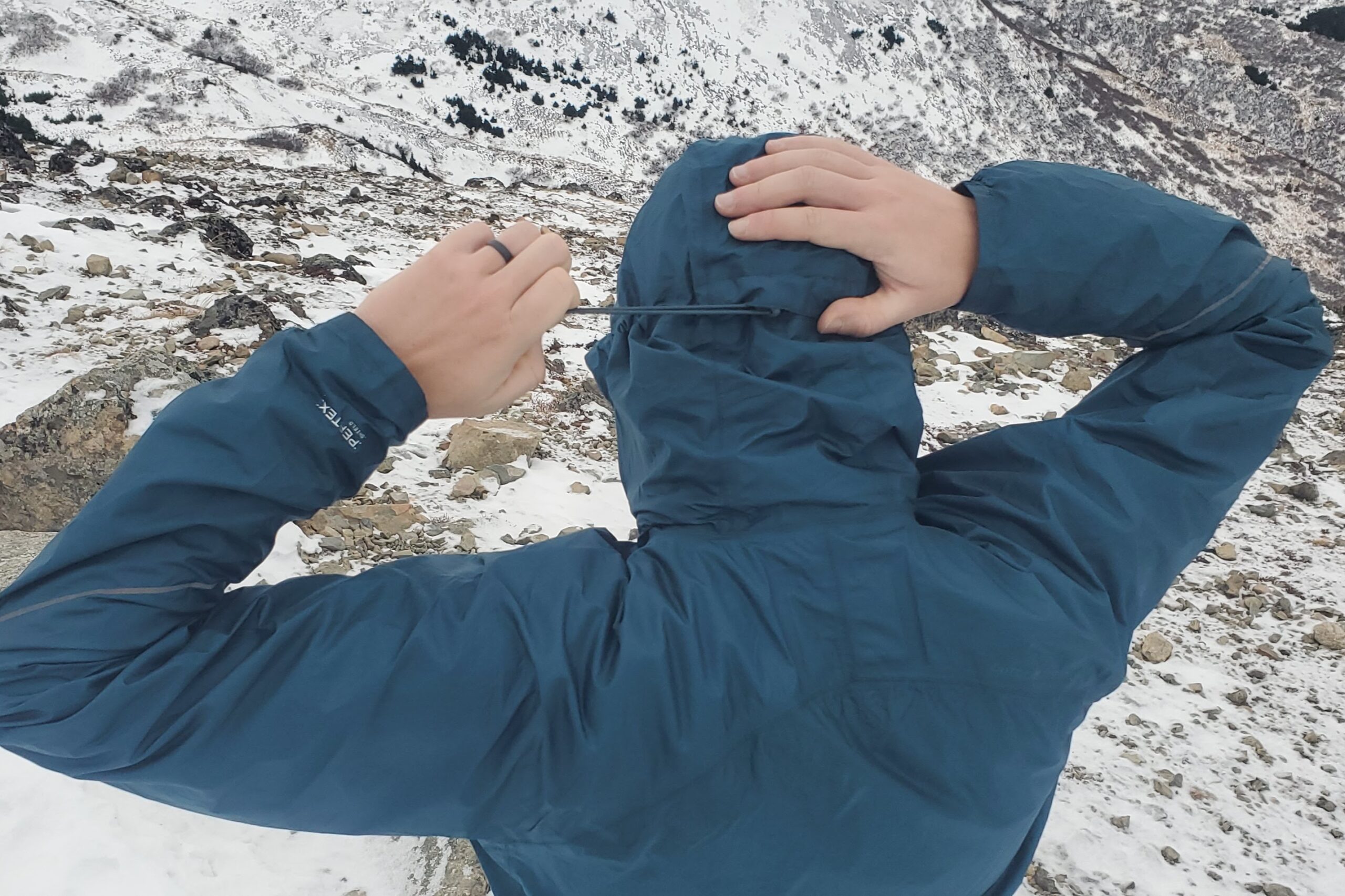 A man tightens the hood of his rain jacket.