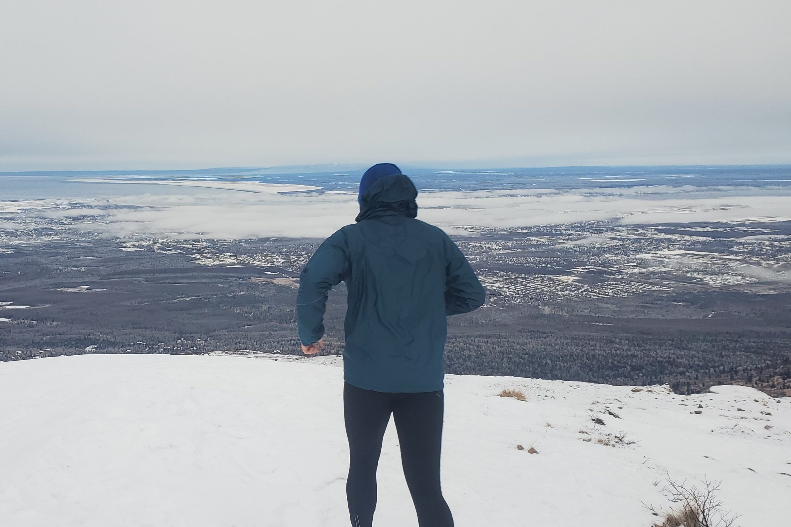 A man runs down a mountain trail in the snow.