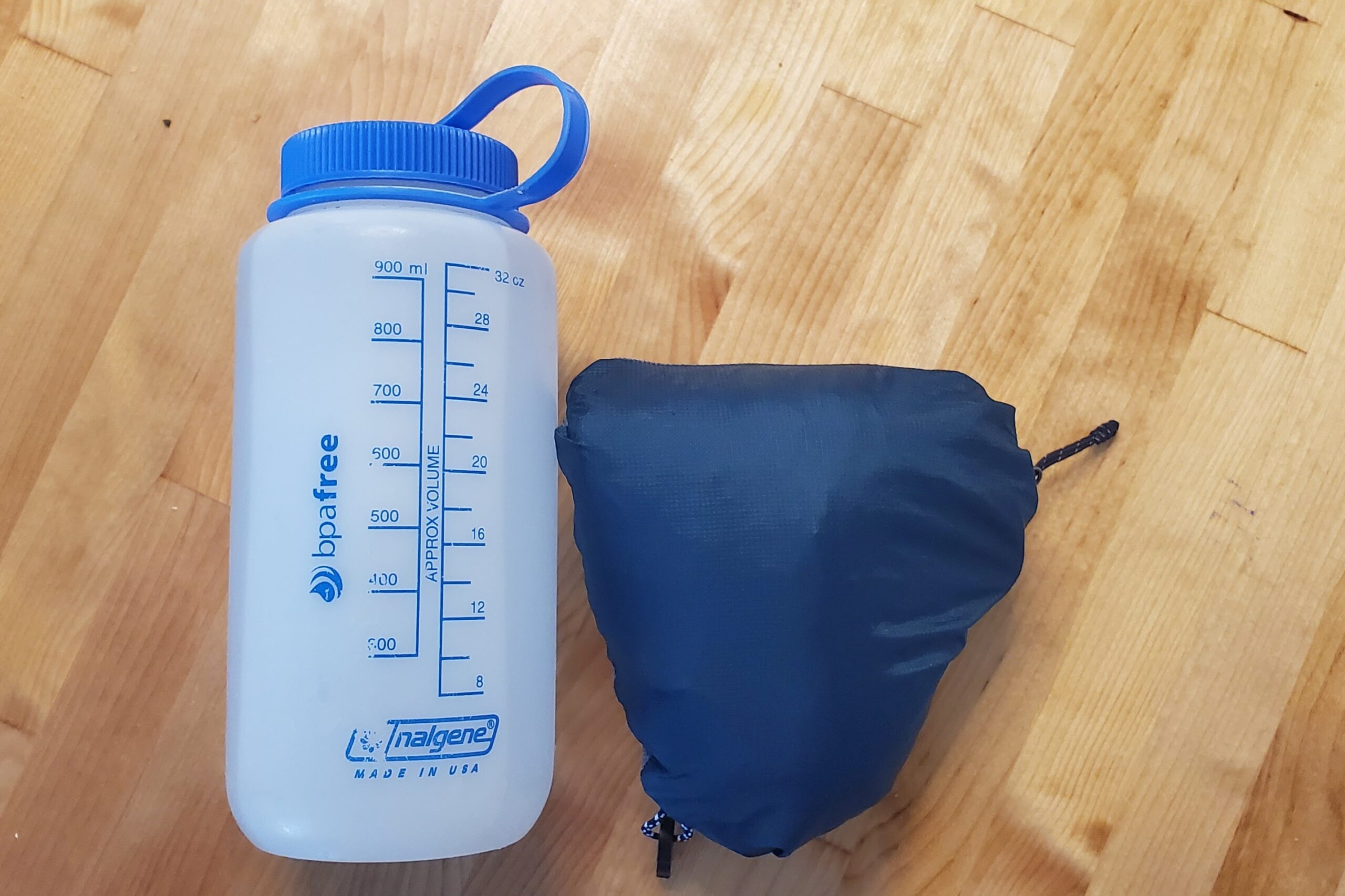 A jacket is packed into it's pocket and compared to a water bottle.