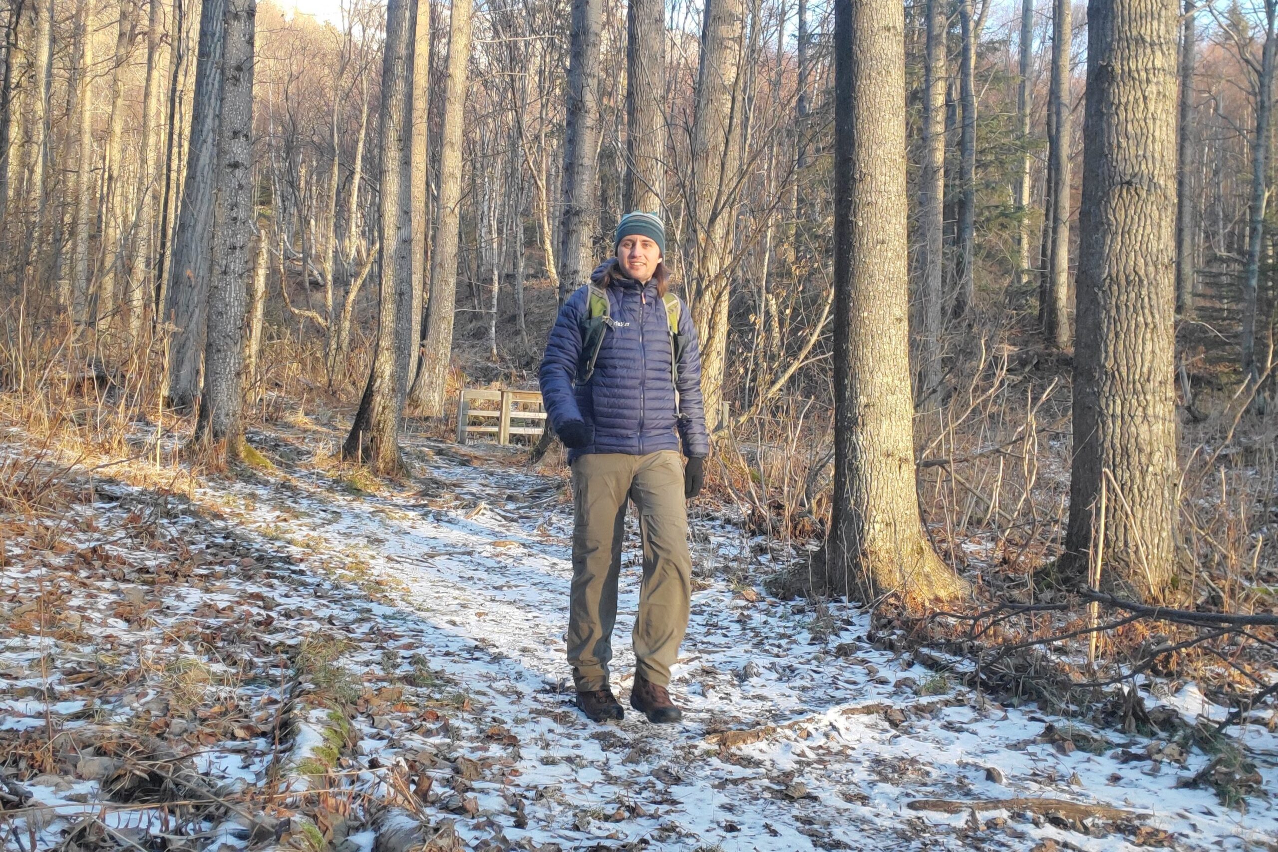 A man walks down a trail in early winter.