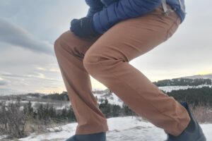 A man crouches on a snowy trail.