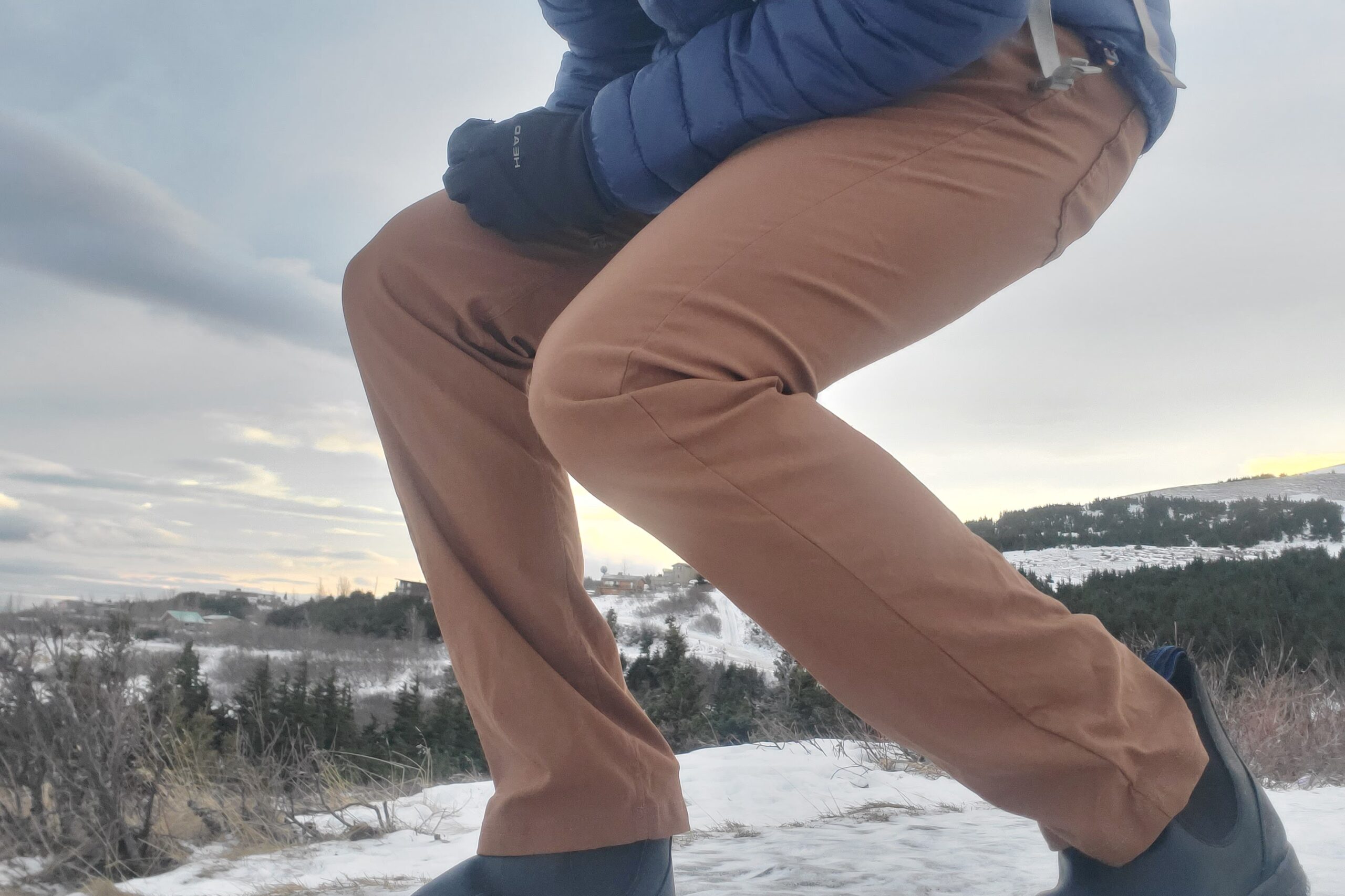 A man crouches on a snowy trail.