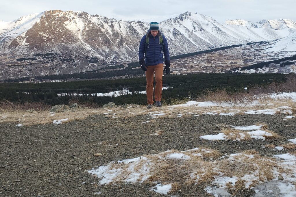 A man hikes with a snowy mountain background.