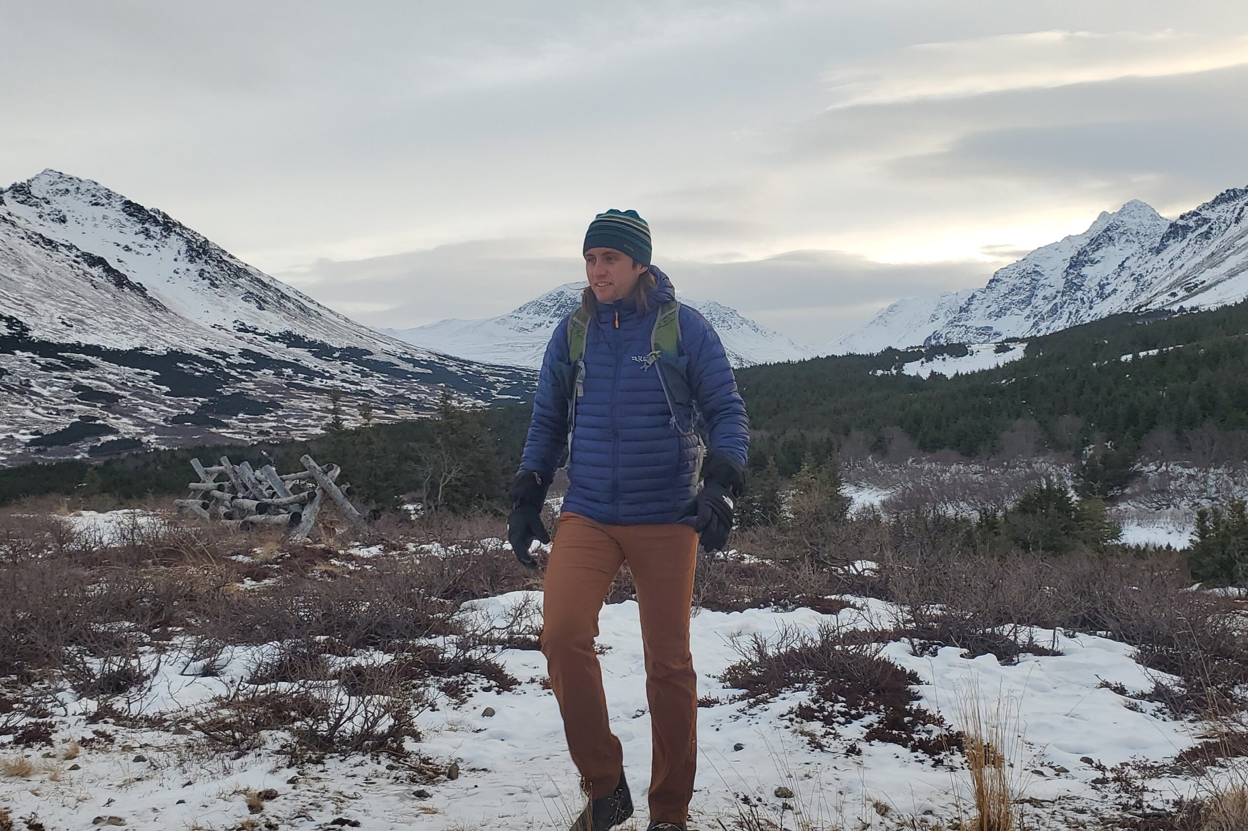 A man walks through subalpine with mountain views.