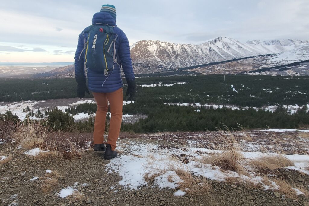 A man walks away from the camera with mountain views.