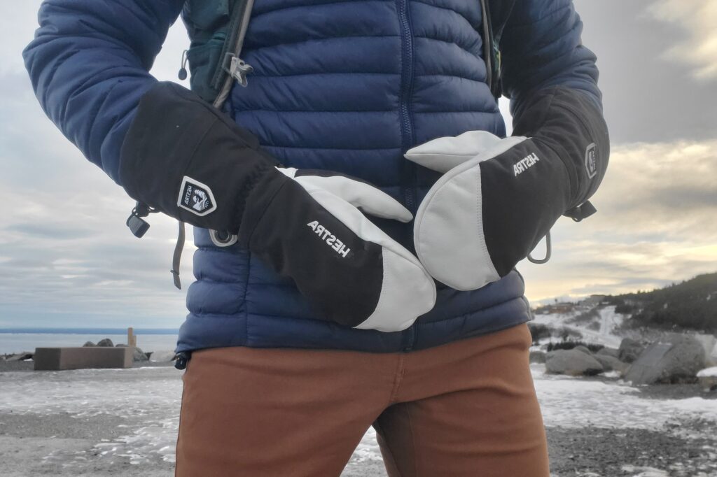 A pair of mittens in front of a jacket.