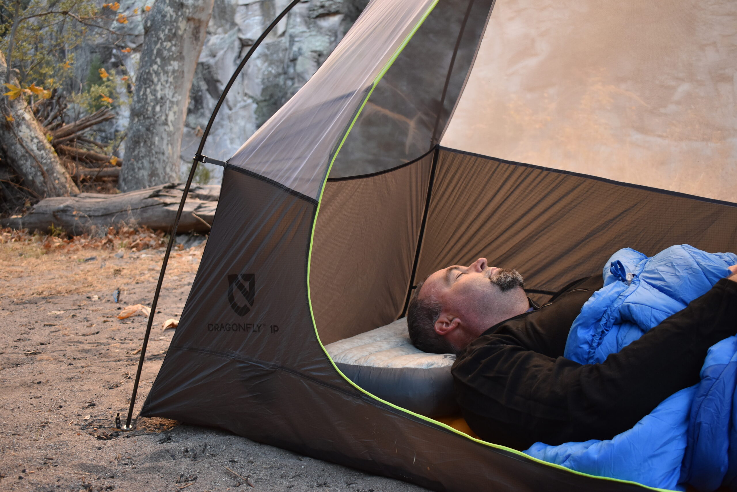 The author resting on the Sea to Summit Aeros Down Pillow in a tent with gray cliffs in the background