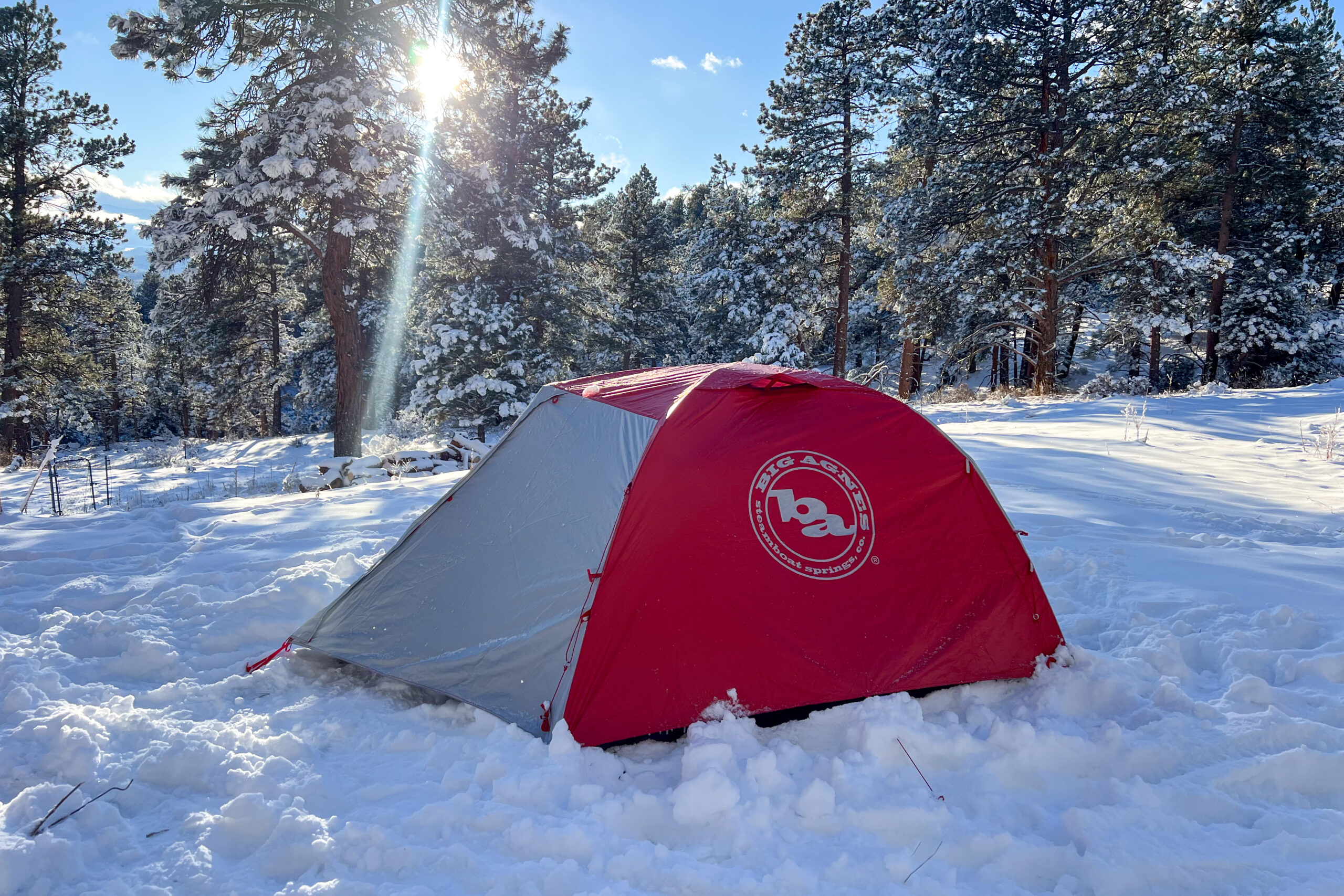 Big Agnes Copper Spur Expedition tent lit by morning sun rays in a snowy forest.