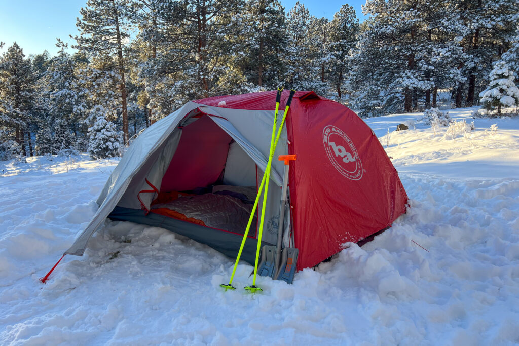 Big Agnes Copper Spur Expedition tent set up in snow with trekking poles and shovels leaning against it.