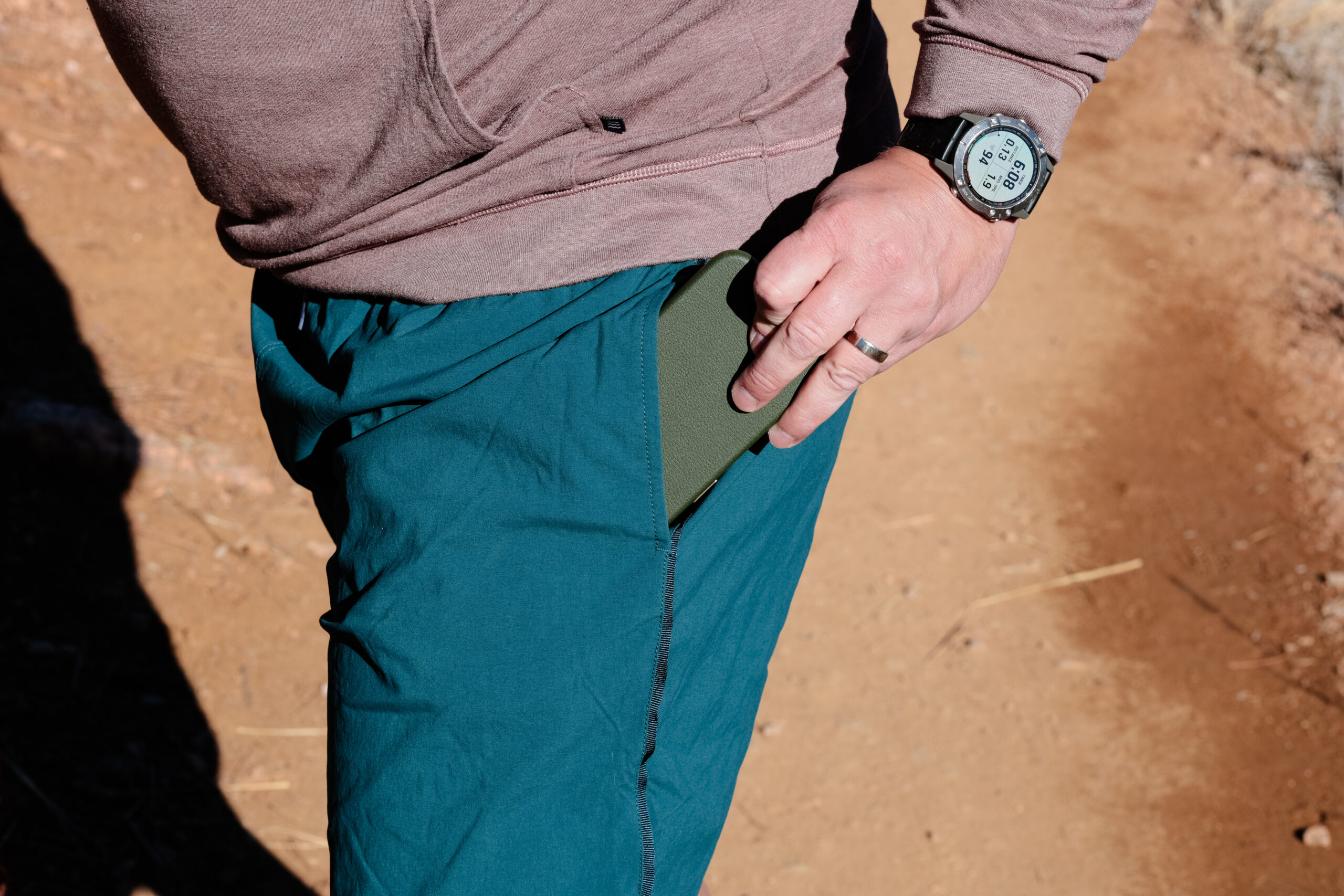 Close up of a hand pulling a phone out of a pocket on green shorts.