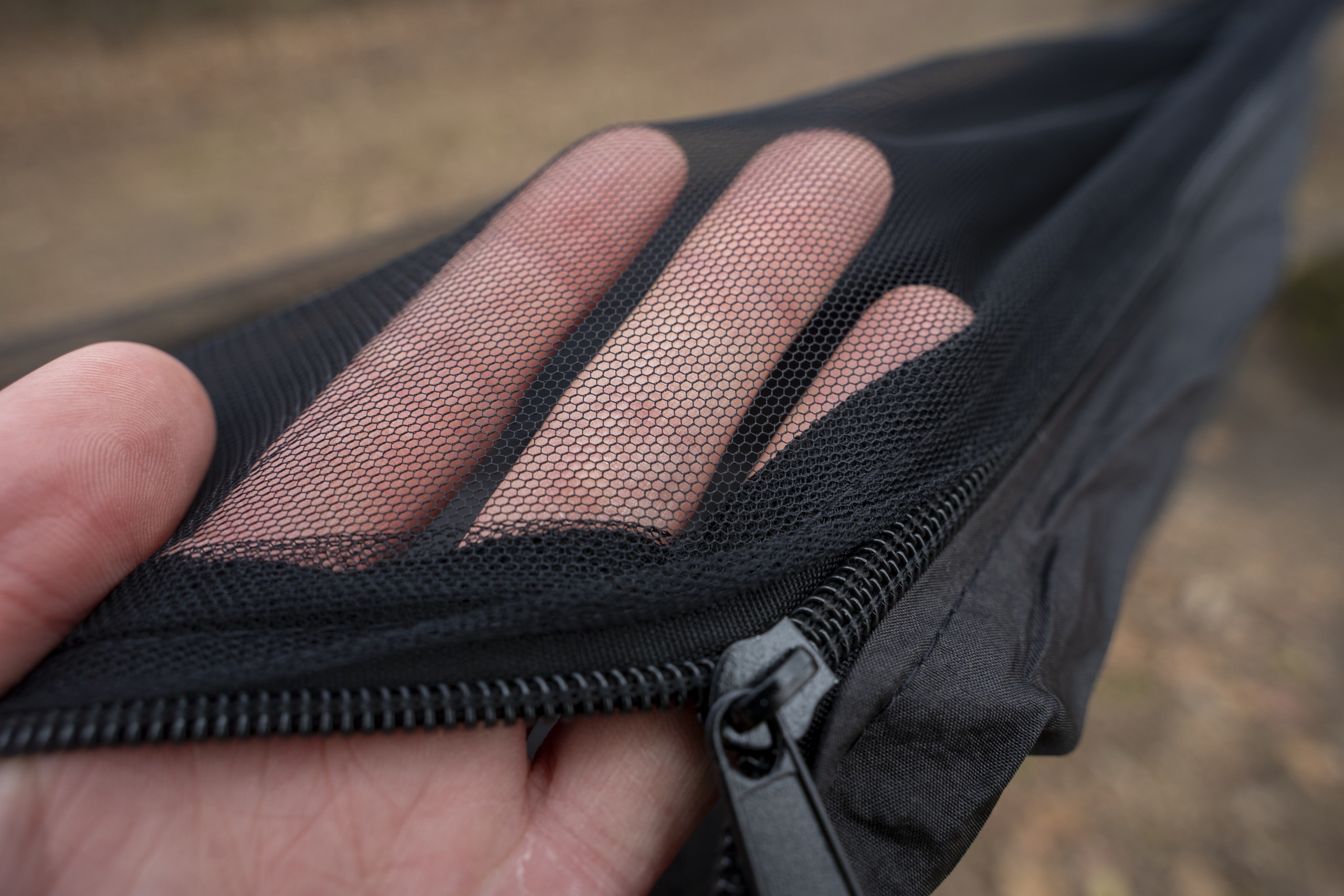 a hand holds the mesh netting of a hammock