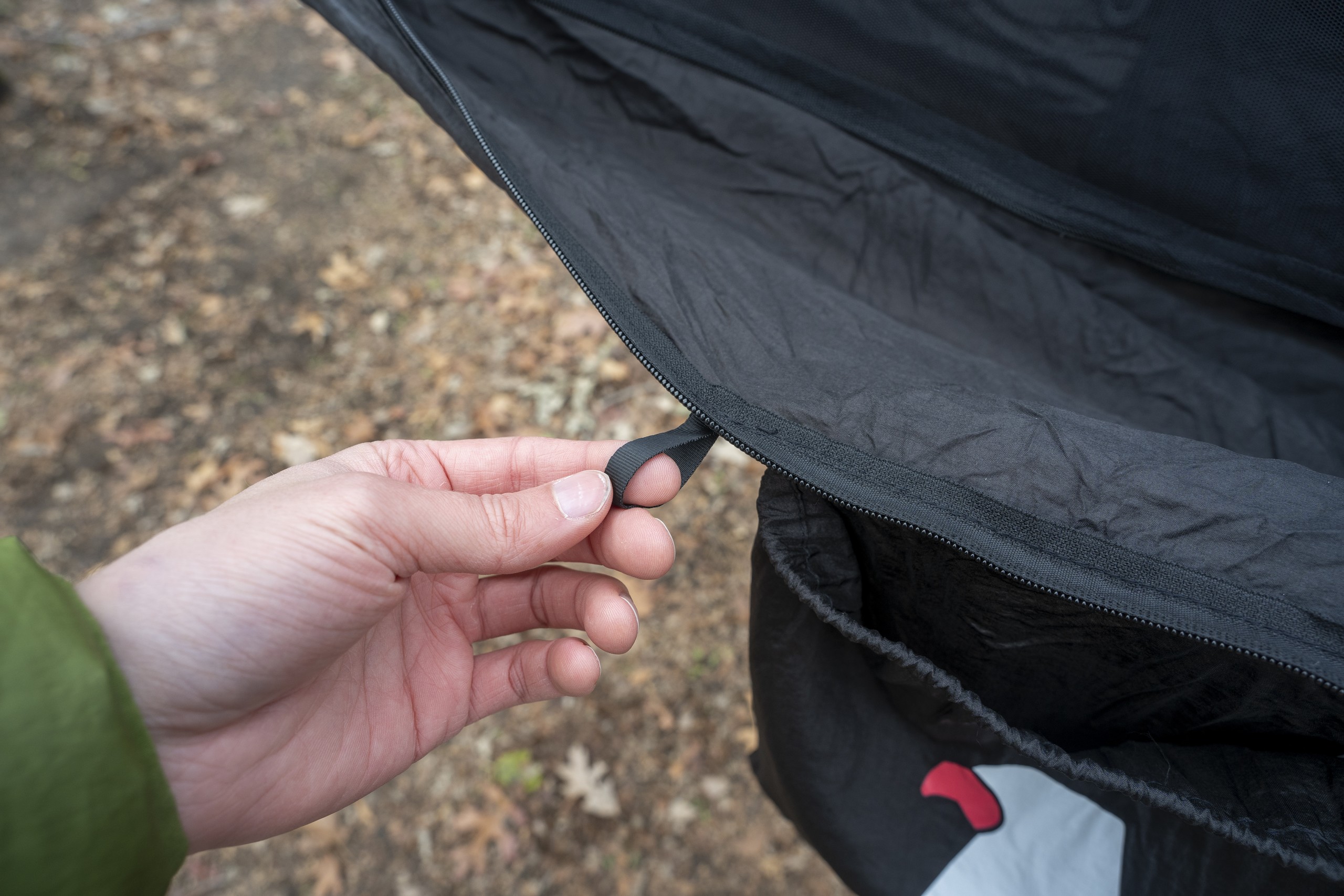 a hand holds a small hook on elastic attached to a hammock body