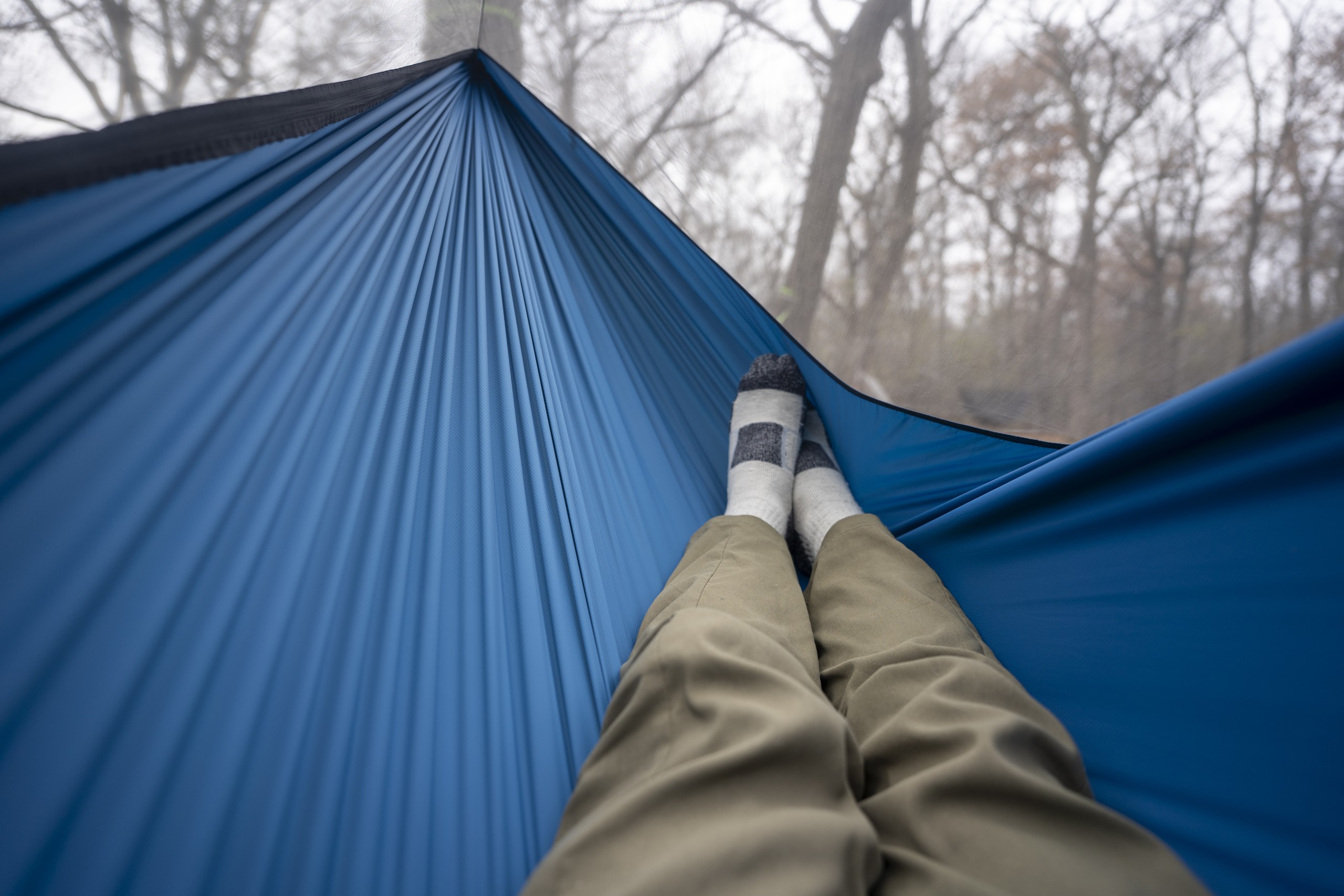 a pair of legs extend into a hammock from a point of view perspective