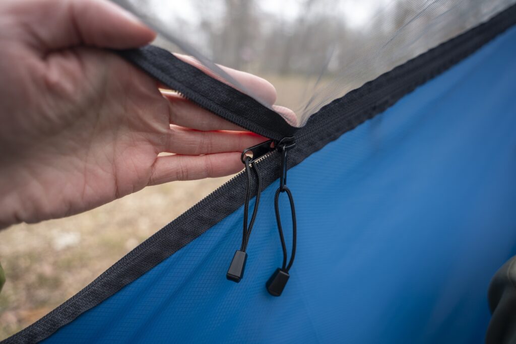 a hand holds a hammock zipper open