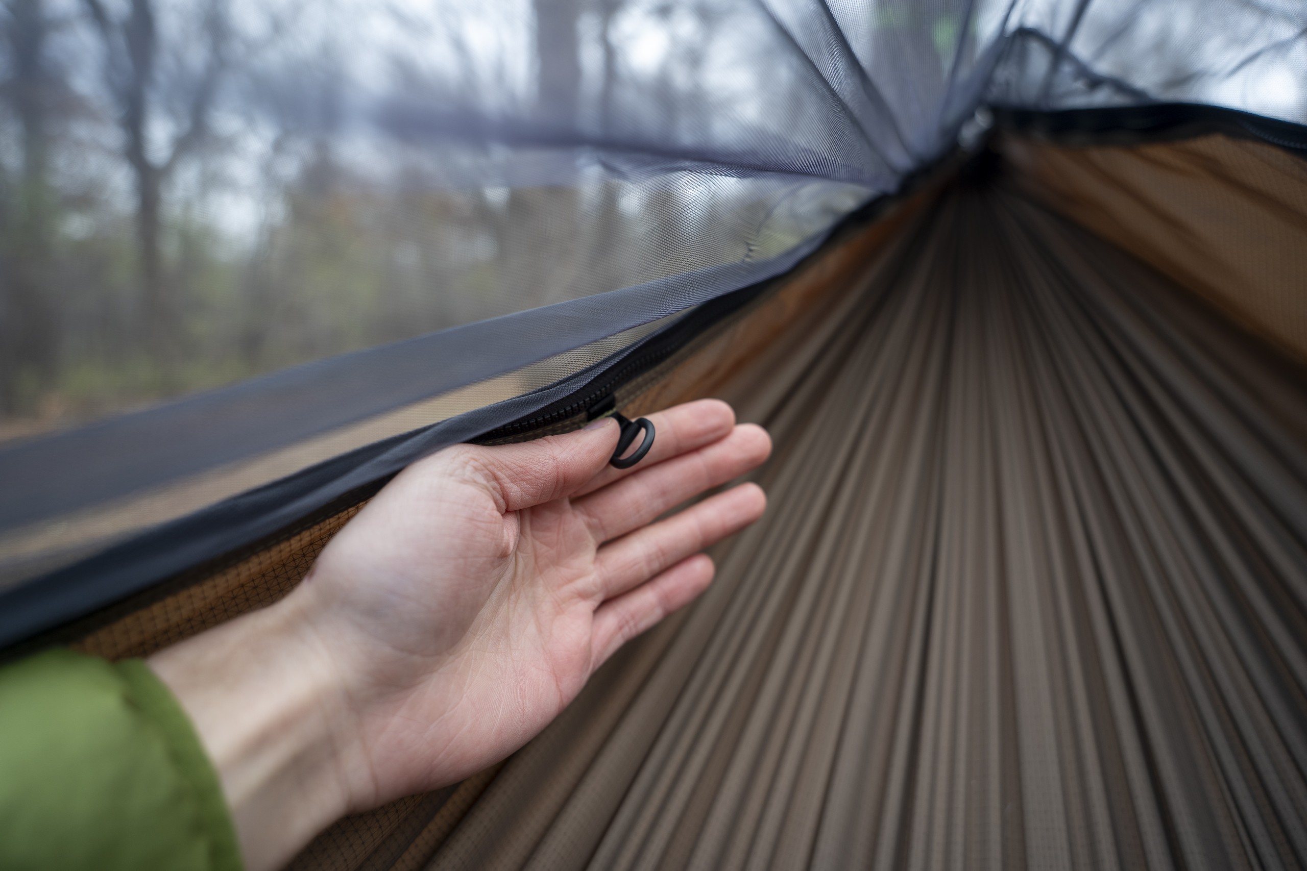 a hand holds a d ring on the interior of a hammock