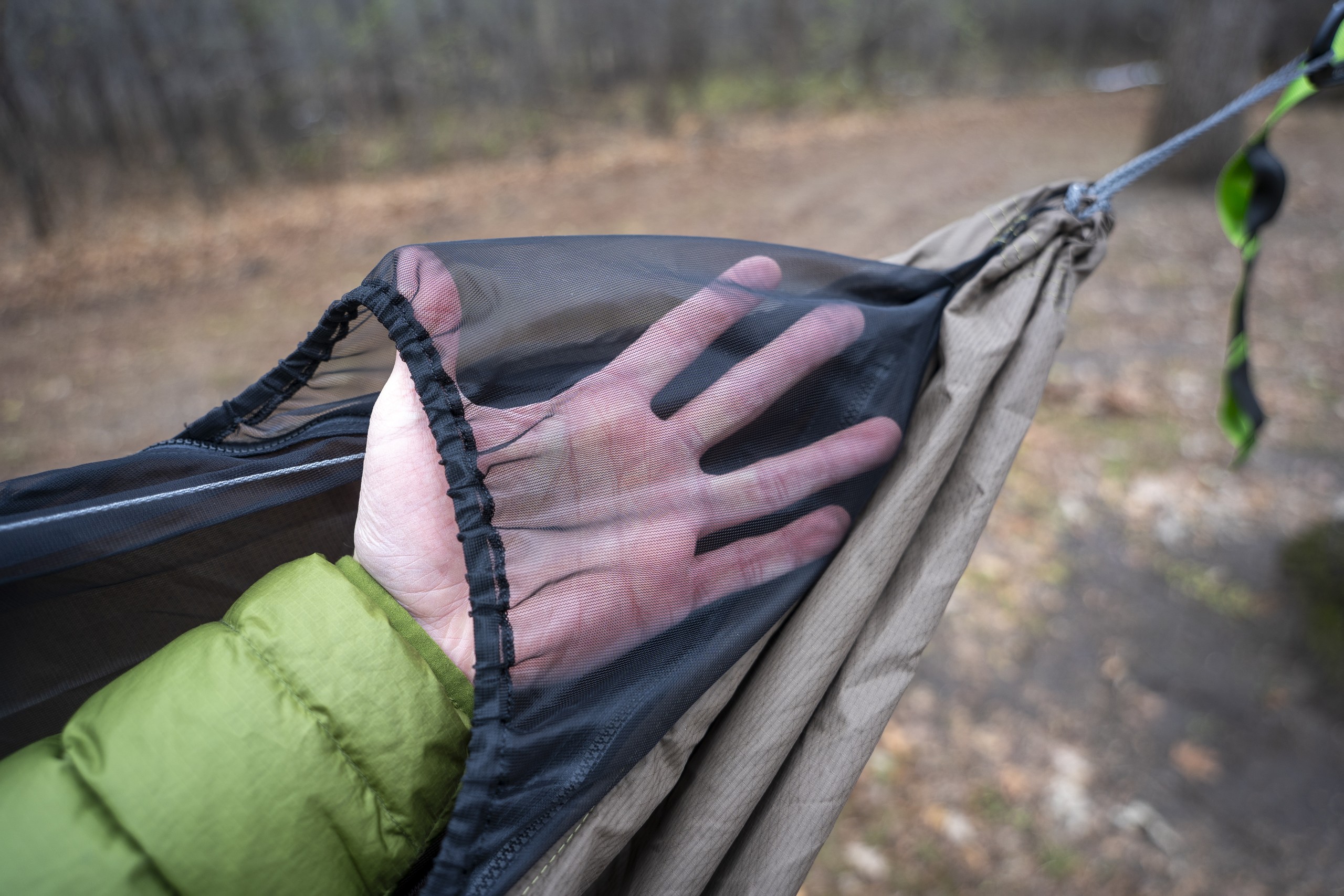 a hand holds mesh attached to the end of a hammock