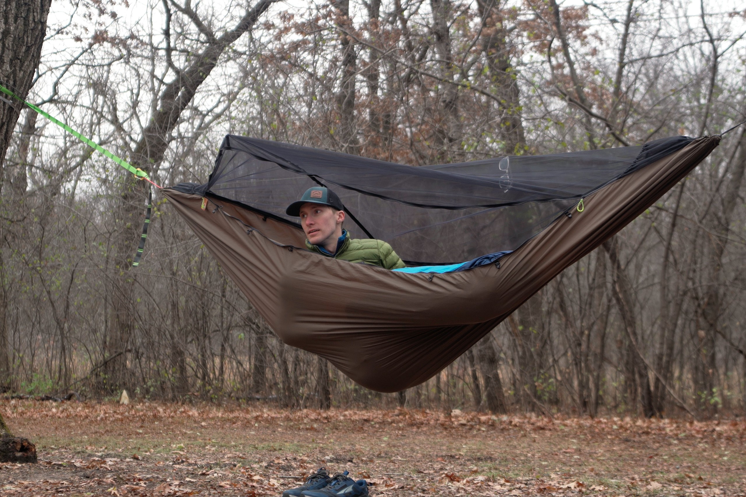 A man lays in a green hammock