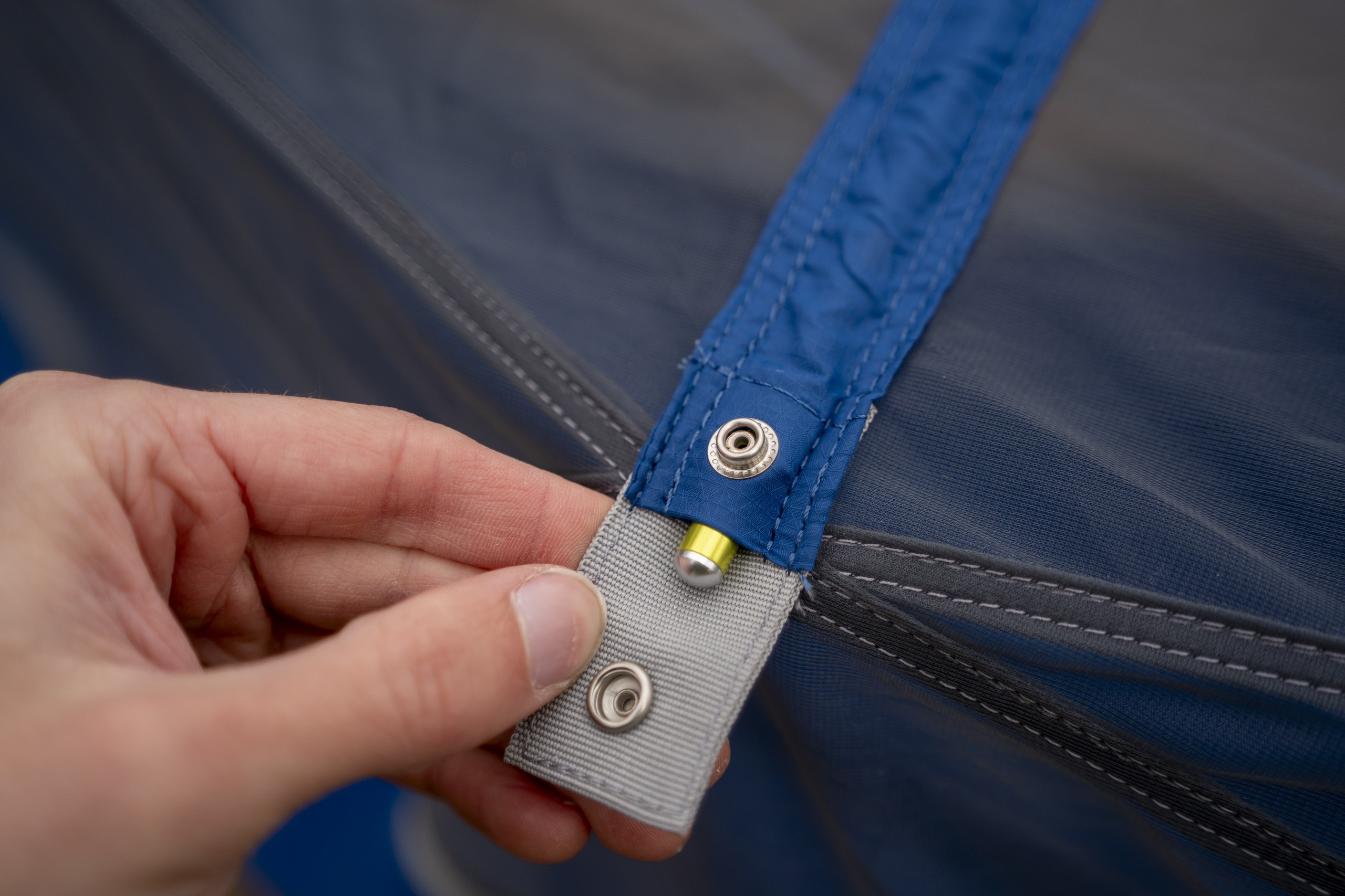 a hand holds open a snap on a hammock