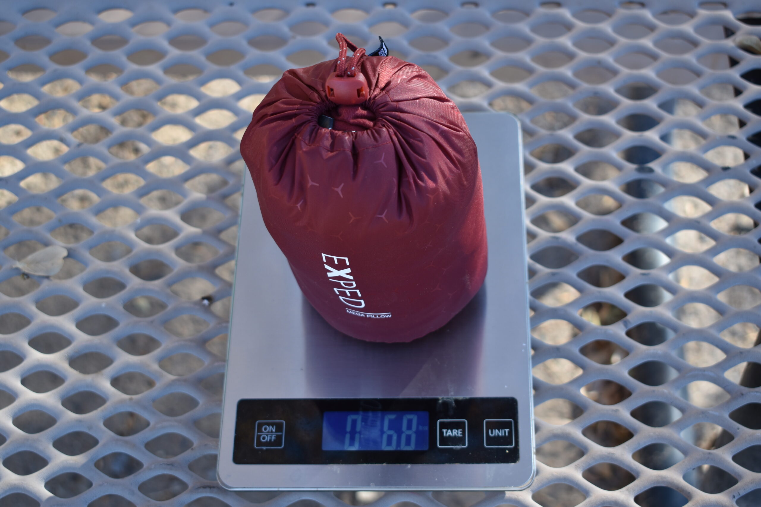 The Exped Mega Pillow sets on a kitchen scale that reads 6.8 ounces