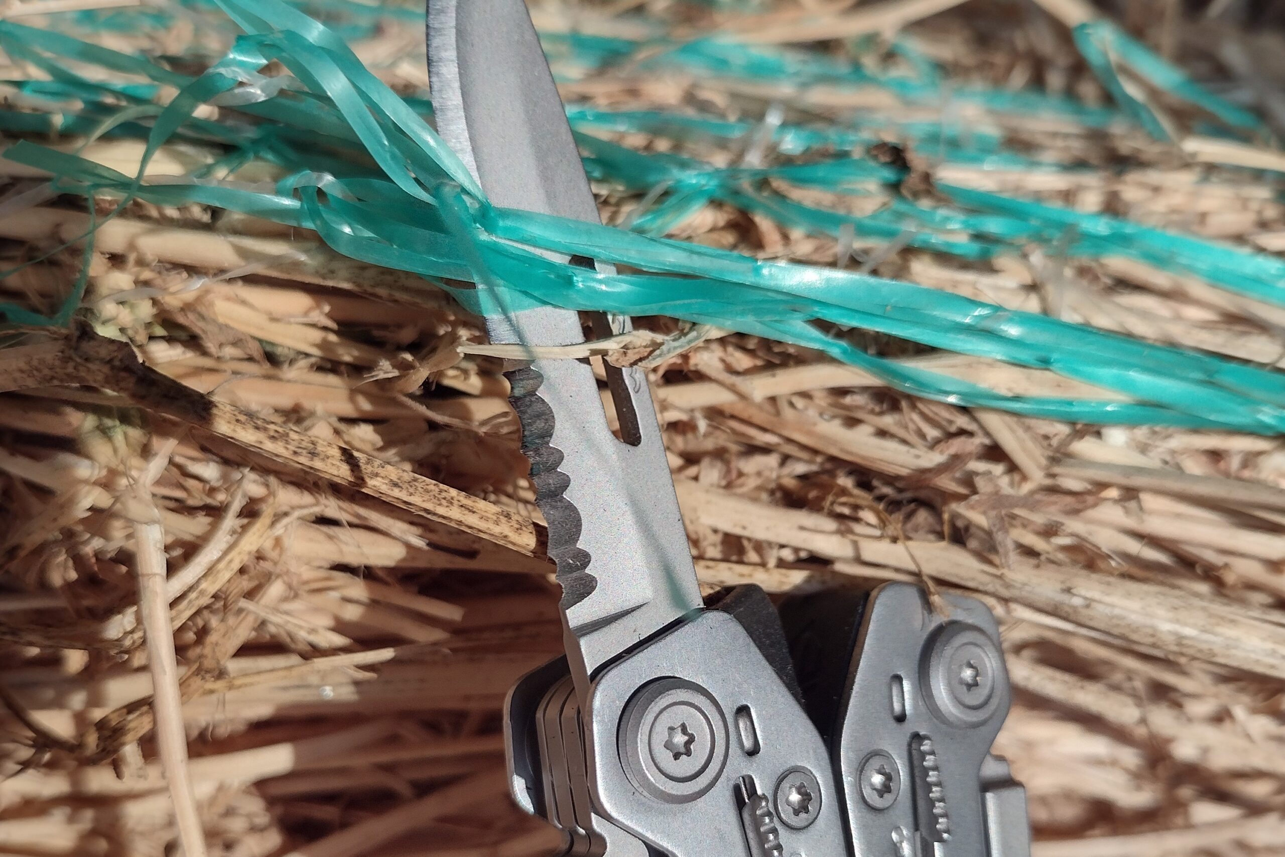 The Gerber Suspension NXT with its knife blade extended, cutting through hay bale netting.