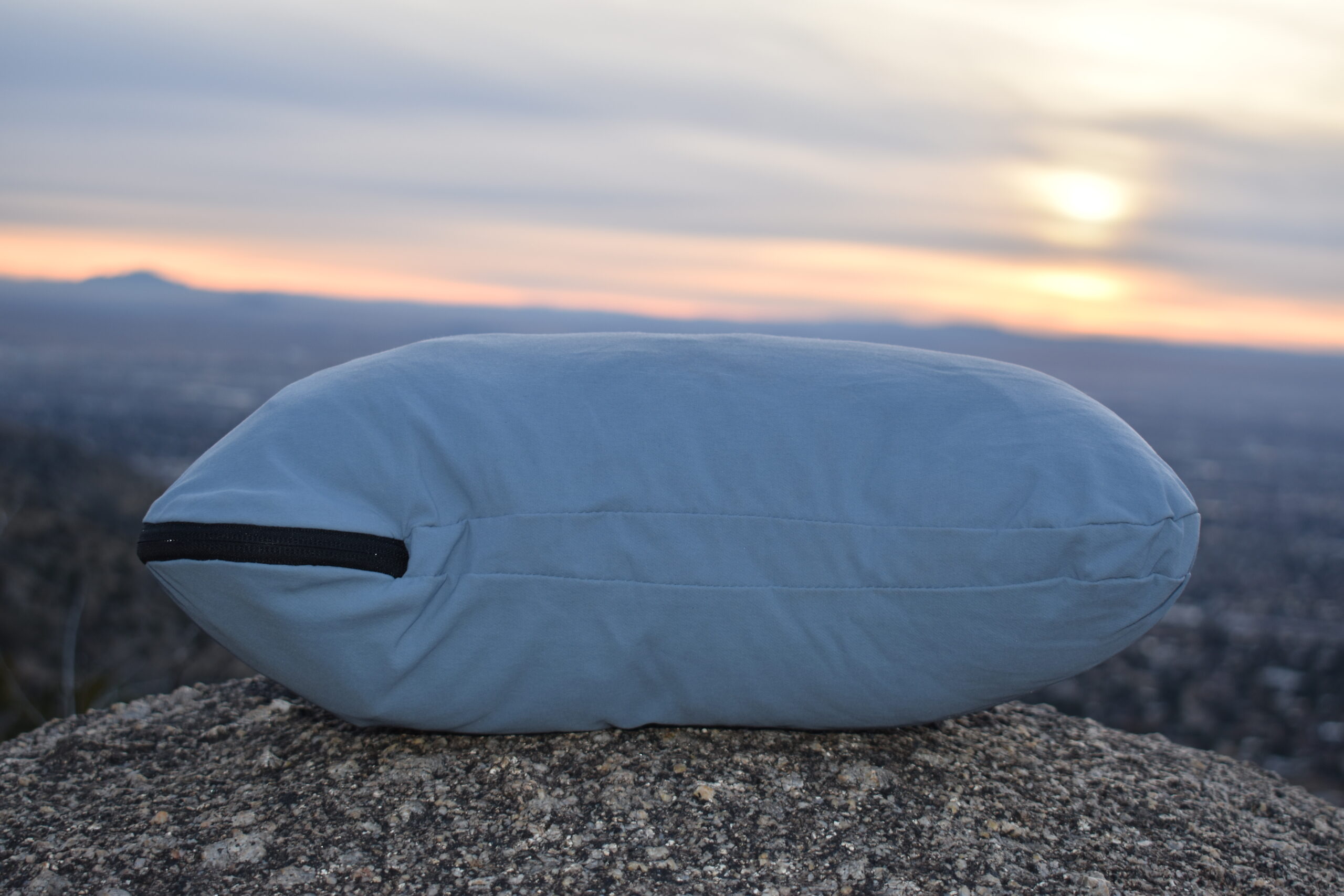 Close up of HEST Camp Pillow on a boulder with the sun setting over the mountains in the background