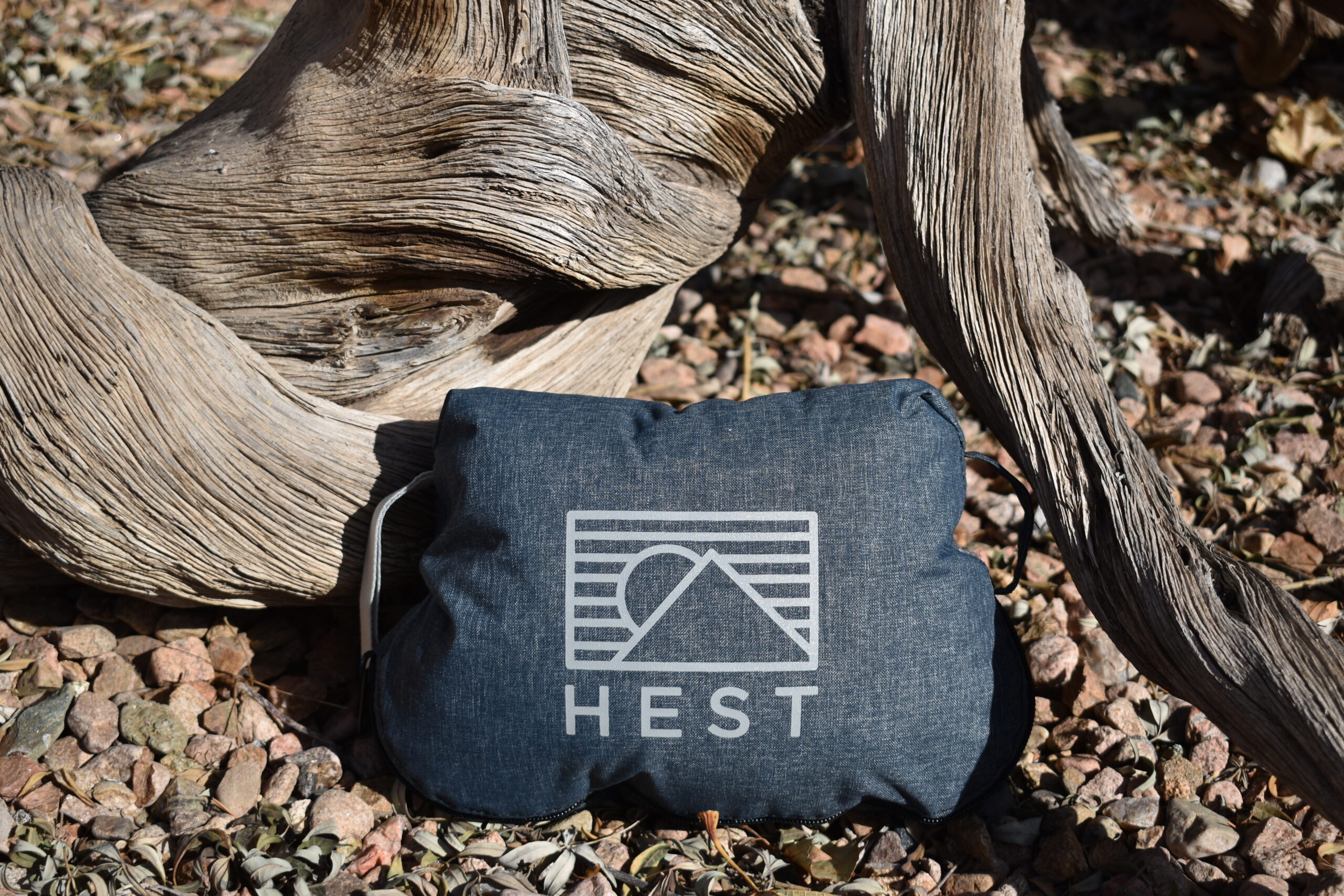 Close up of the HEST Camp Pillow in its stuff sack in front of an interesting piece of wood