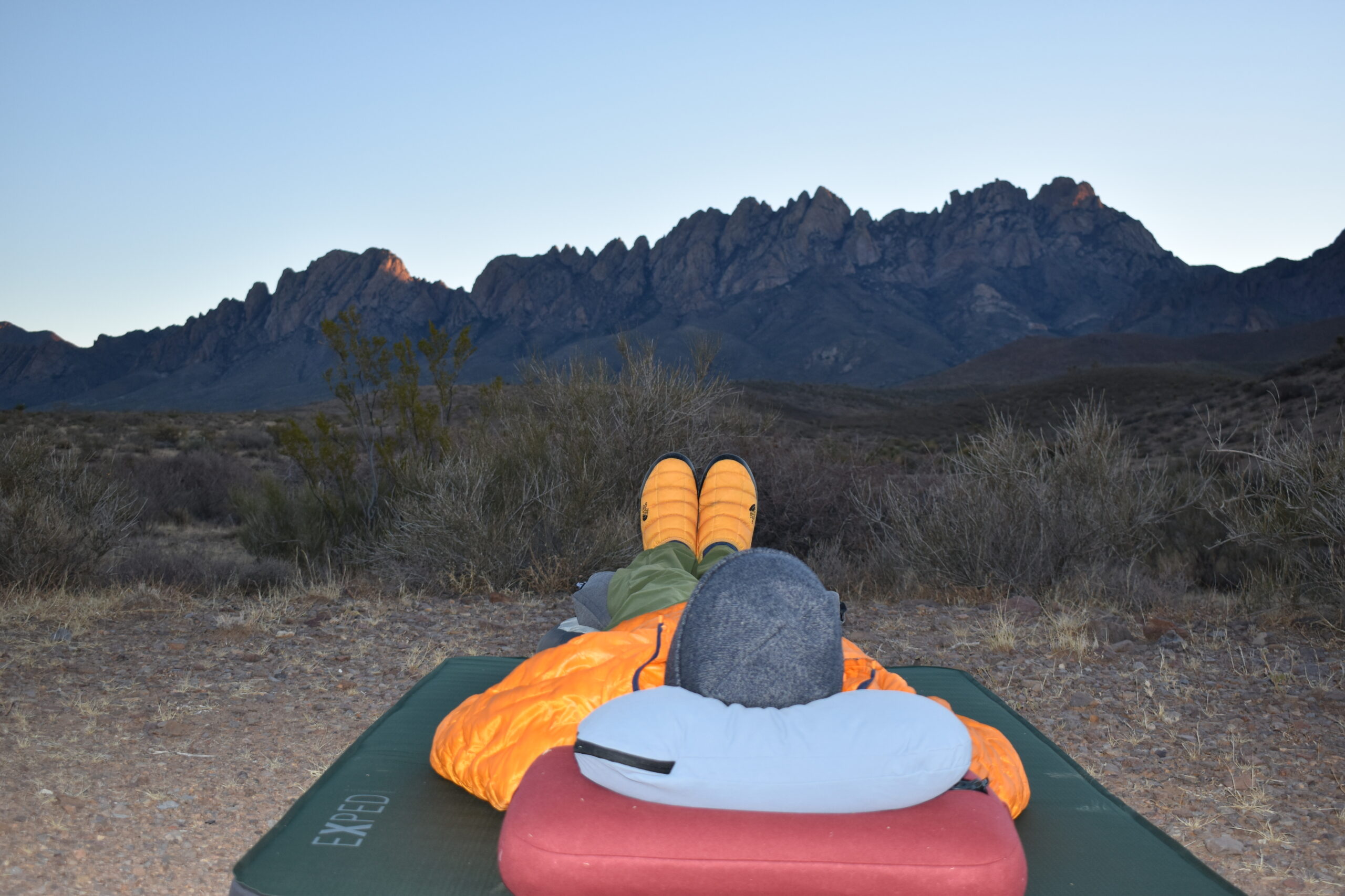 The author staring at New Mexico's Organ Mountains at sunset while reclining on the HEST Camp Pillow (top) and ExPed Mega Pillow (bottom)