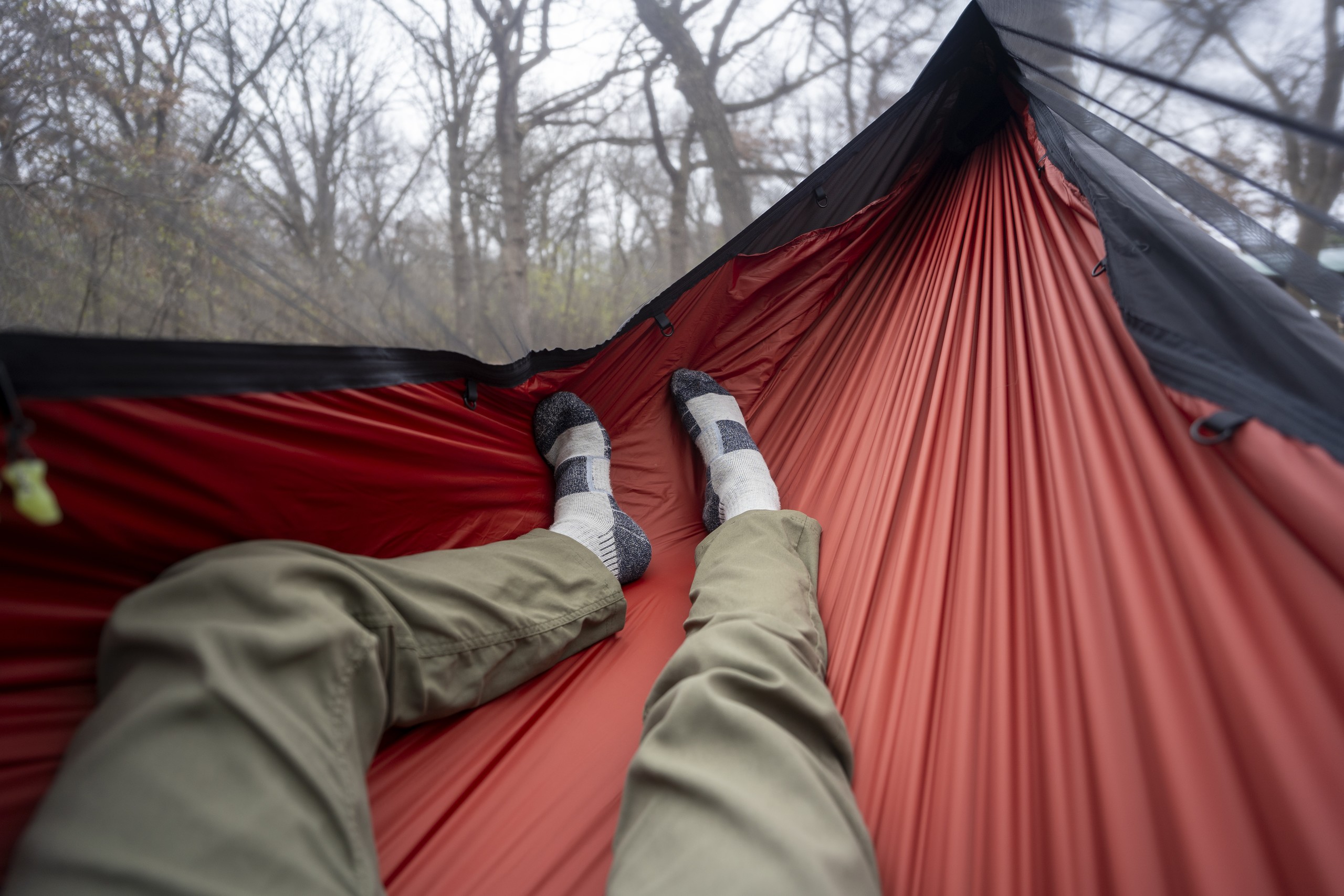 a pair of legs extend into a red hammock body from a point of view perspective